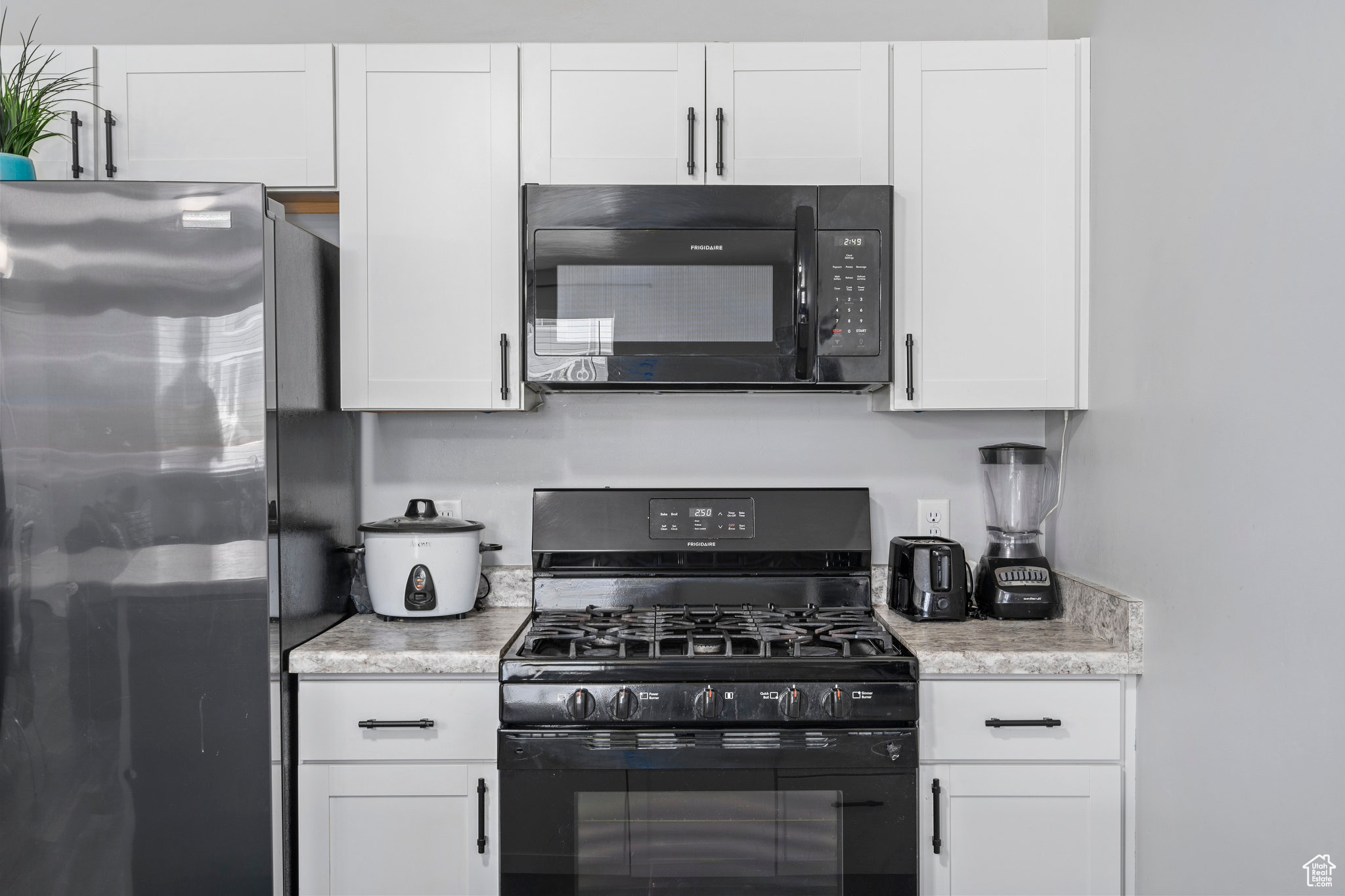 Kitchen with white cabinetry and black appliances