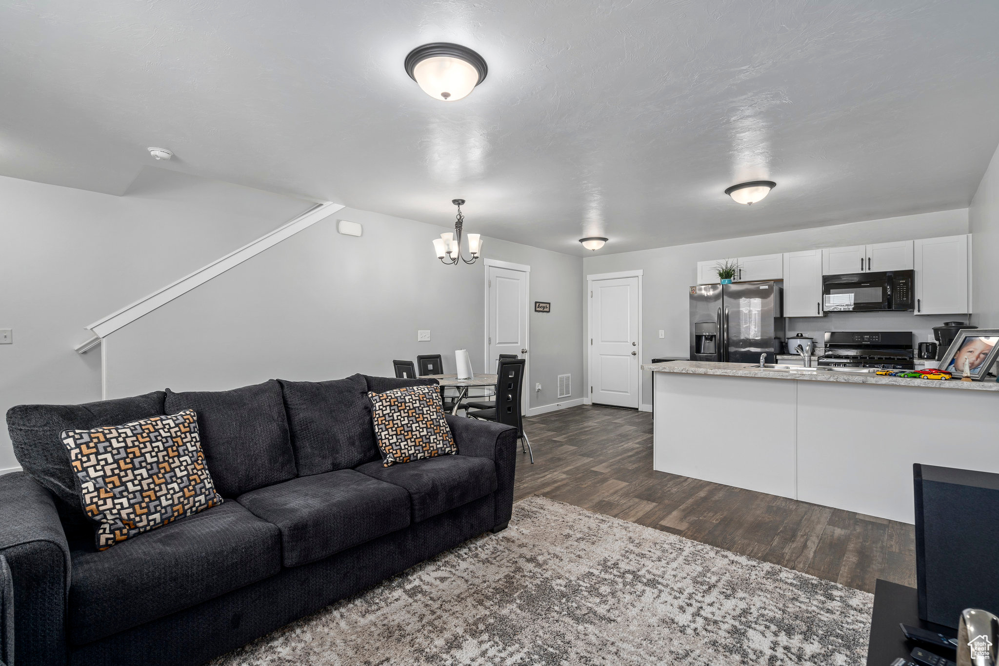 Living room with dark hardwood / wood-style flooring and an inviting chandelier