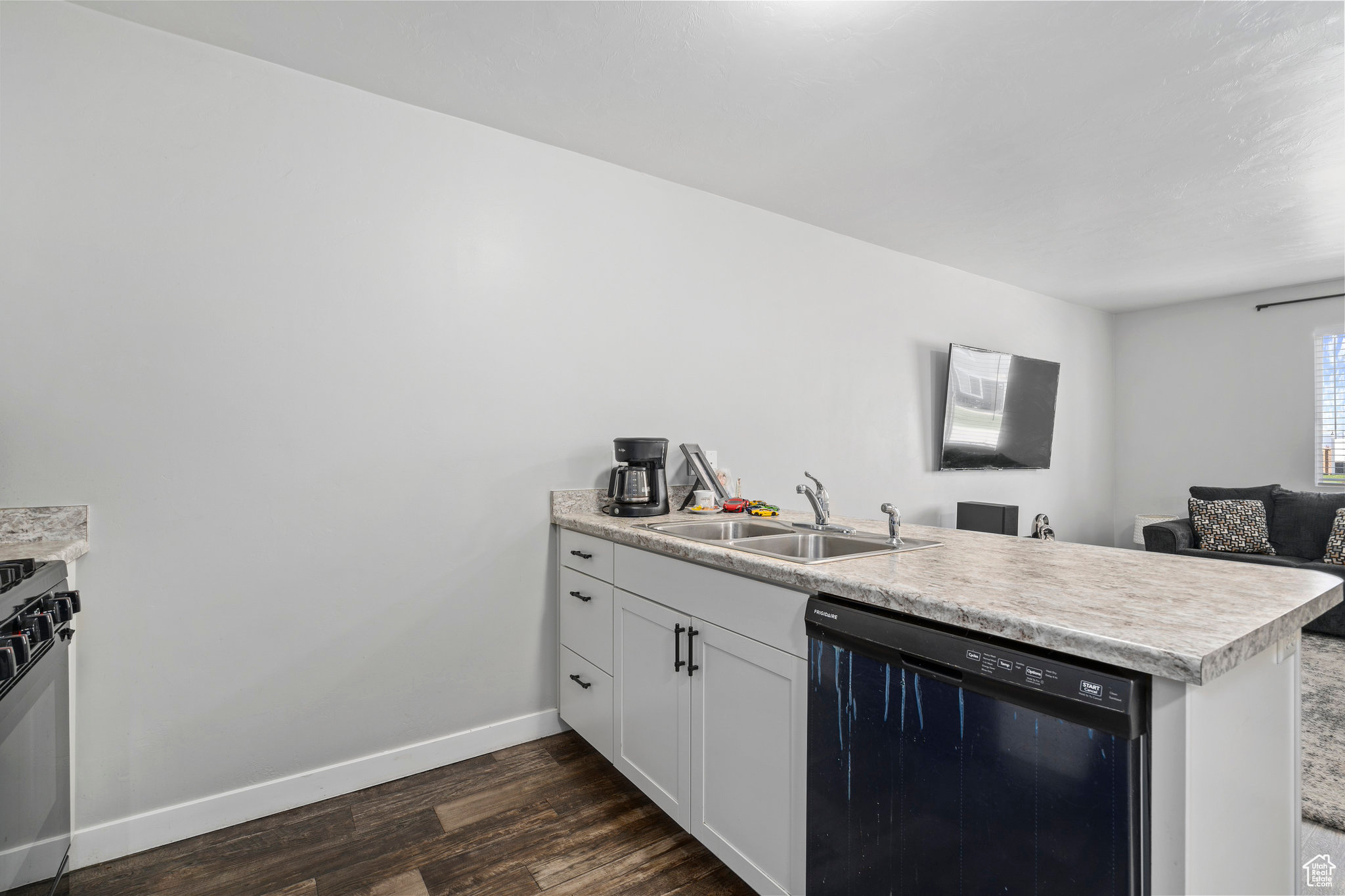 Kitchen featuring dishwasher, sink, dark hardwood / wood-style flooring, kitchen peninsula, and white cabinets