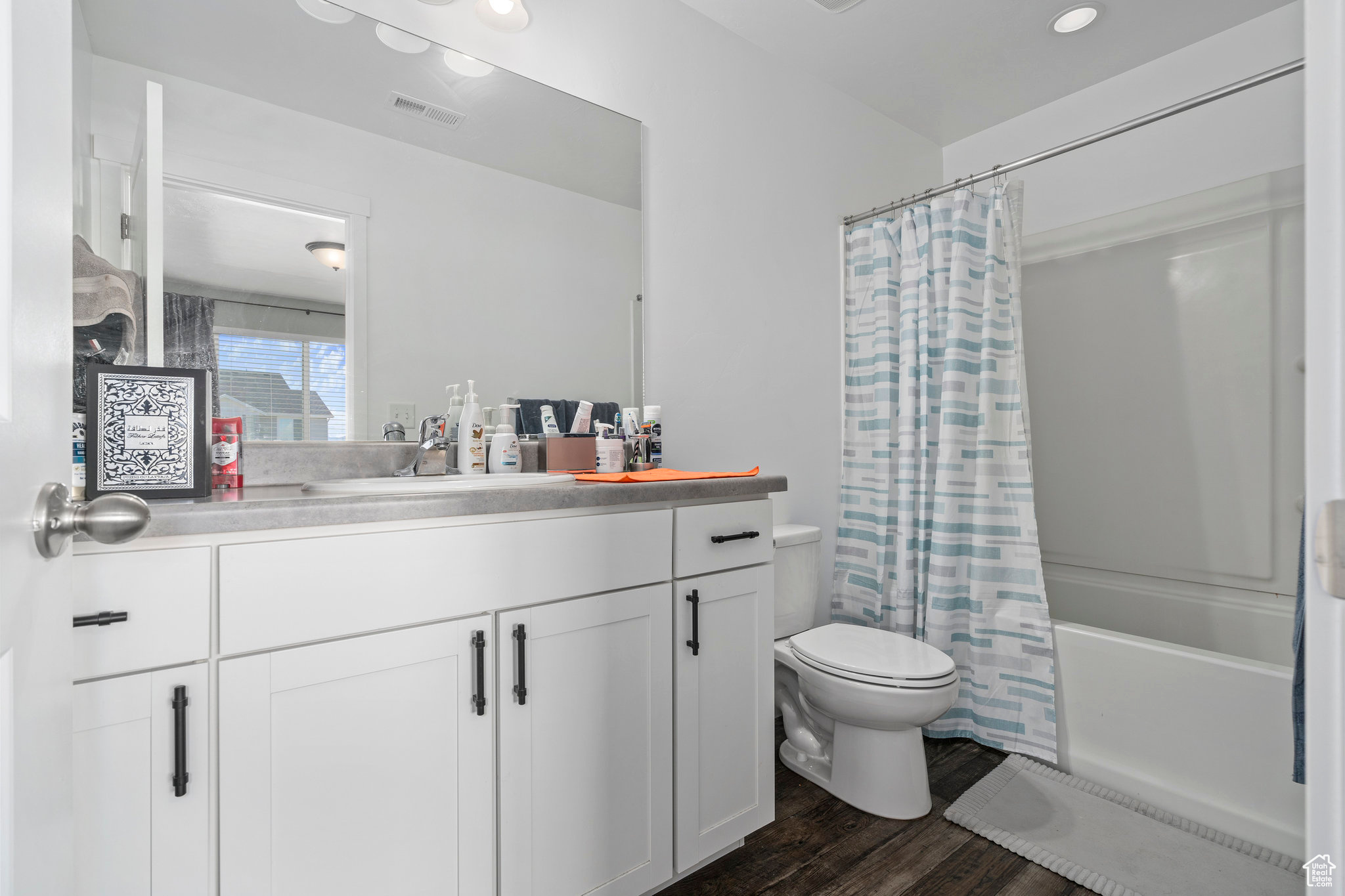 Full bathroom with toilet, vanity, shower / bath combo, and hardwood / wood-style flooring