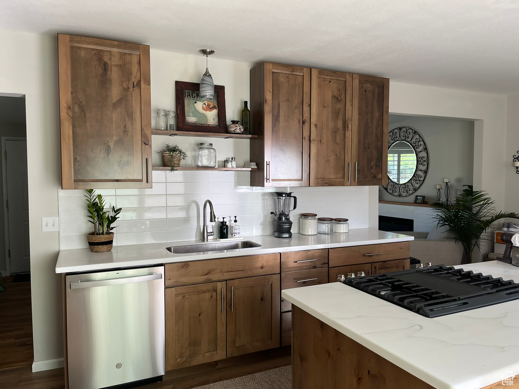 Kitchen with sink, dark wood-type flooring, stainless steel dishwasher, backsplash, and pendant lighting