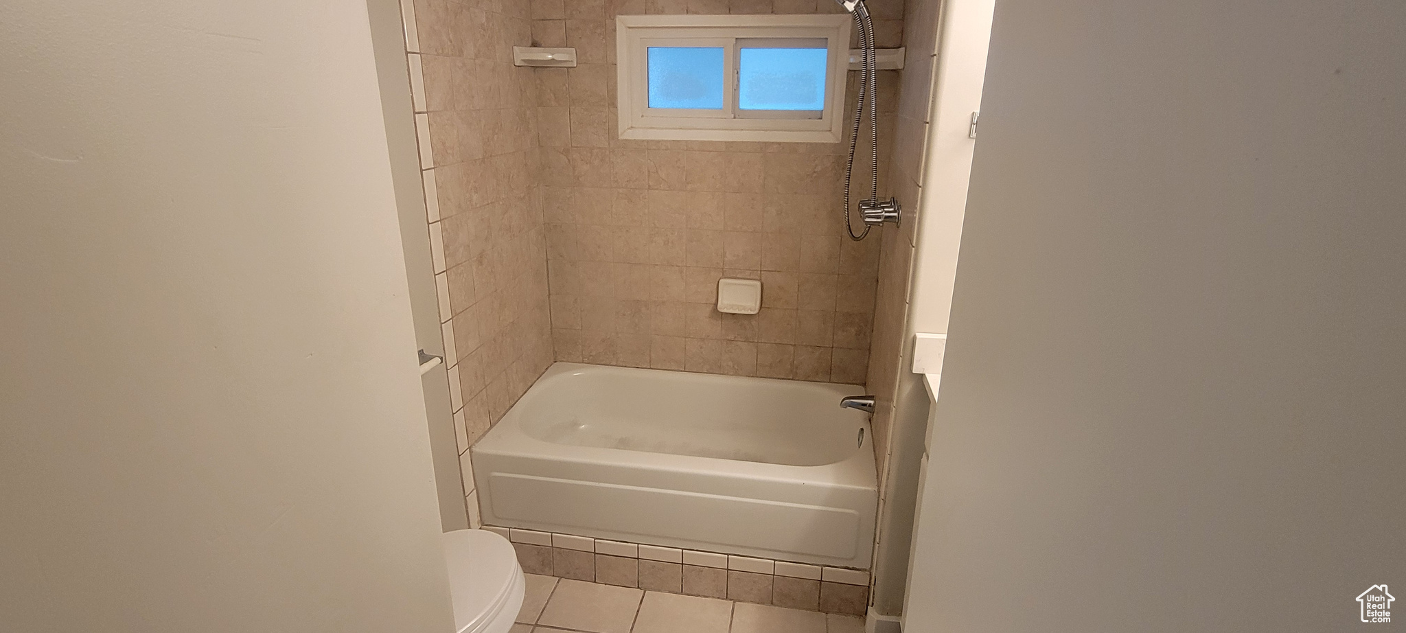 Bathroom with tile patterned flooring, toilet, and tiled shower / bath