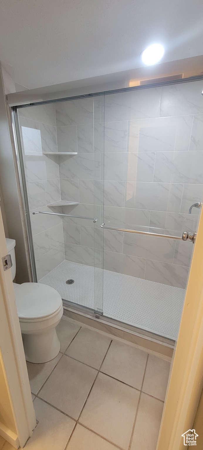 Bathroom featuring tile patterned floors, toilet, and an enclosed shower