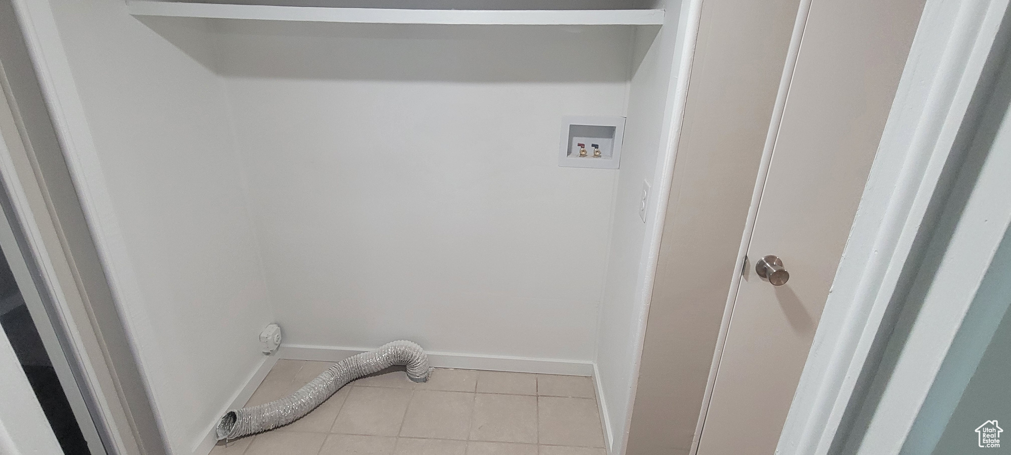 Laundry area featuring washer hookup and light tile patterned flooring