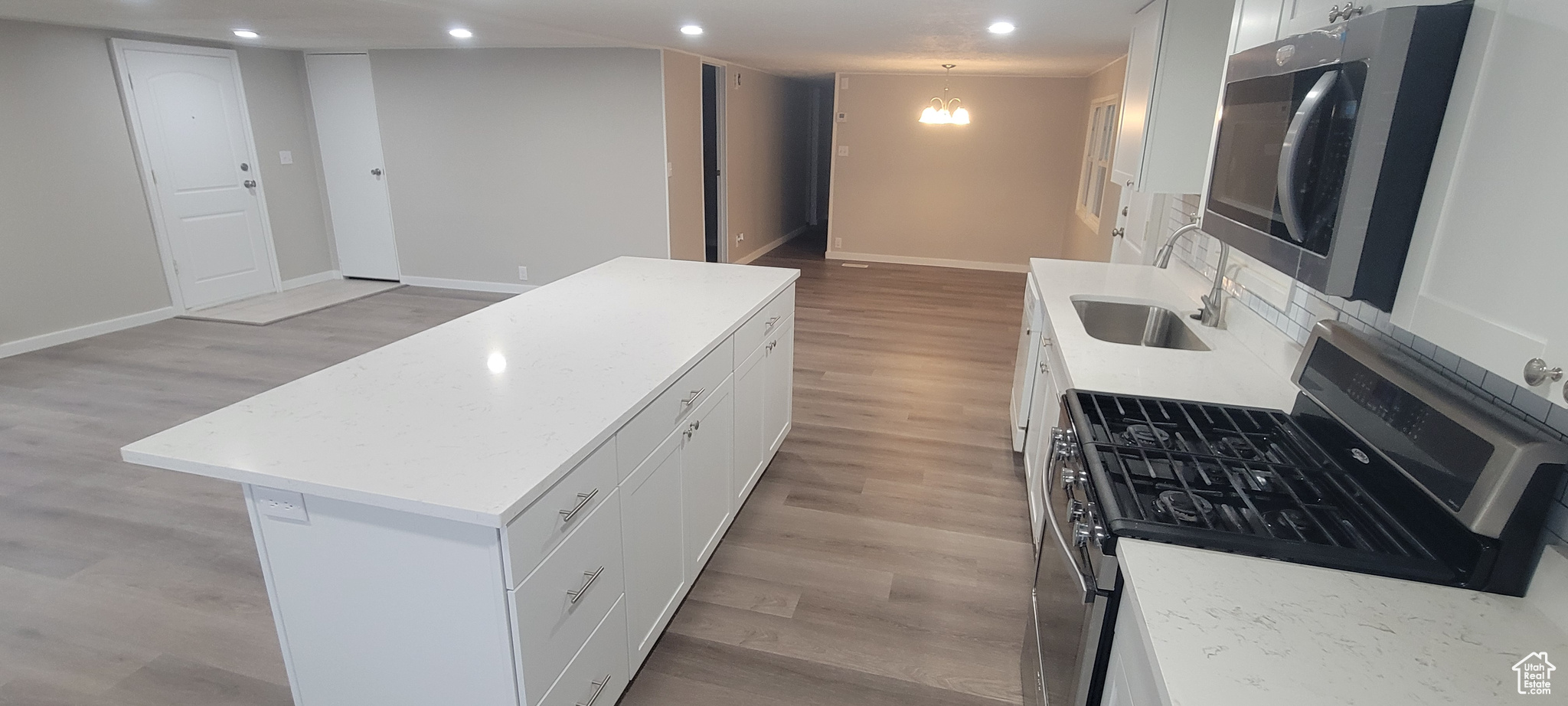 Kitchen with white cabinets, sink, light hardwood / wood-style flooring, a kitchen island, and stainless steel appliances