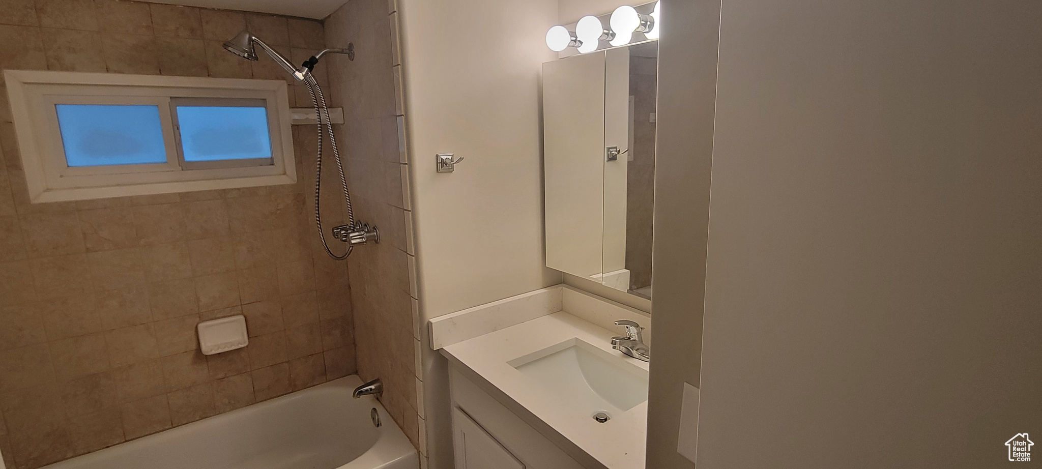 Bathroom with tiled shower / bath combo and vanity