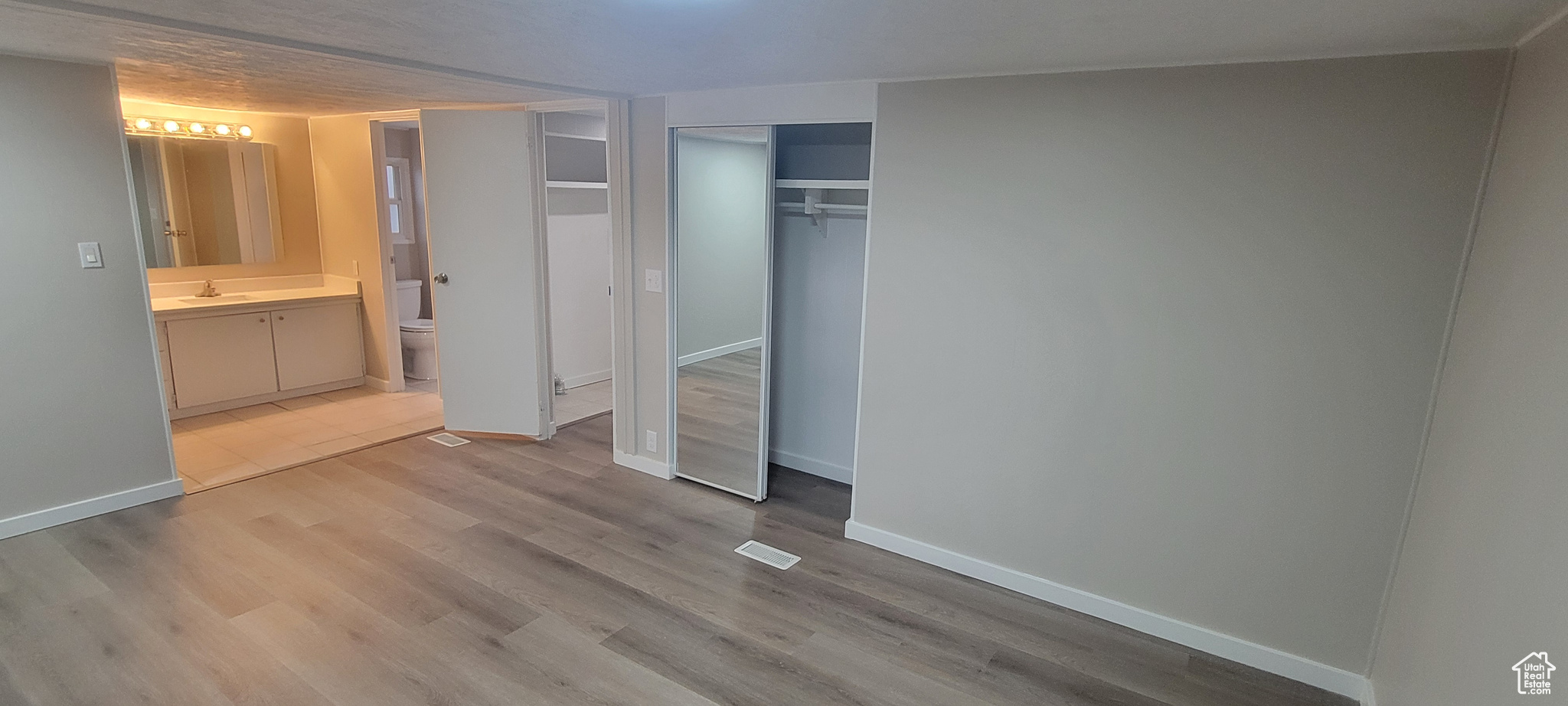 Unfurnished bedroom with connected bathroom, light hardwood / wood-style floors, and sink