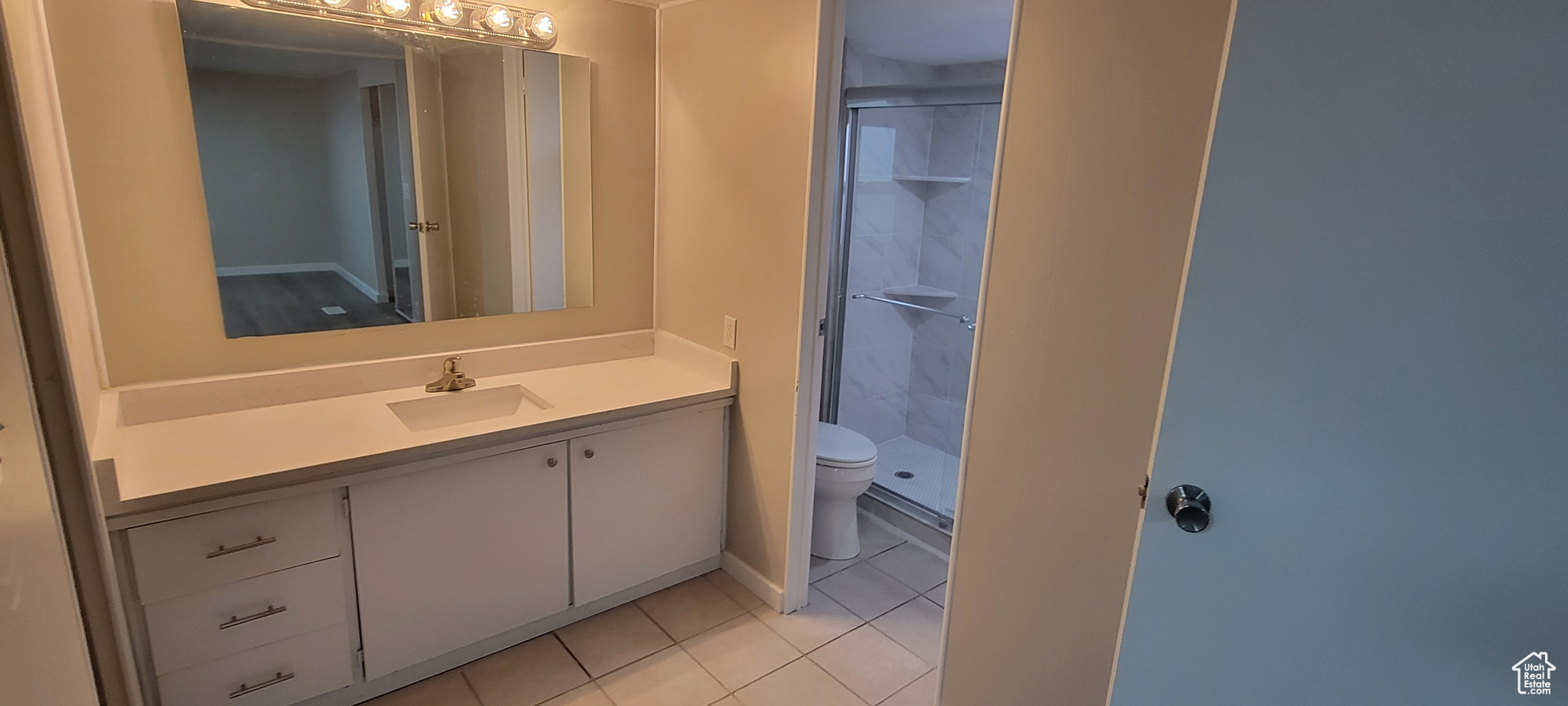 Bathroom with toilet, vanity, tile patterned floors, and walk in shower