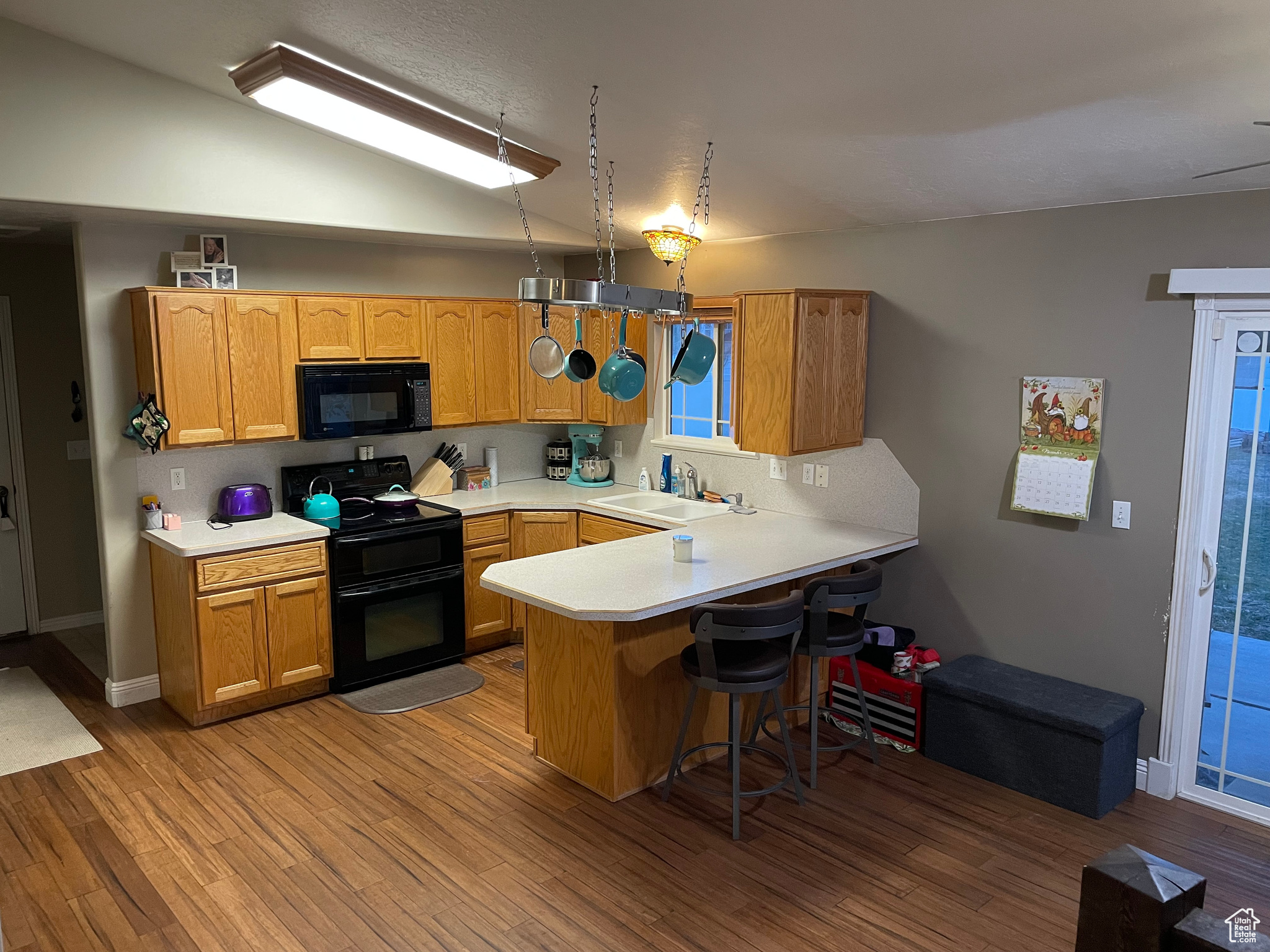 Kitchen featuring kitchen peninsula, sink, black appliances, and light wood-type flooring