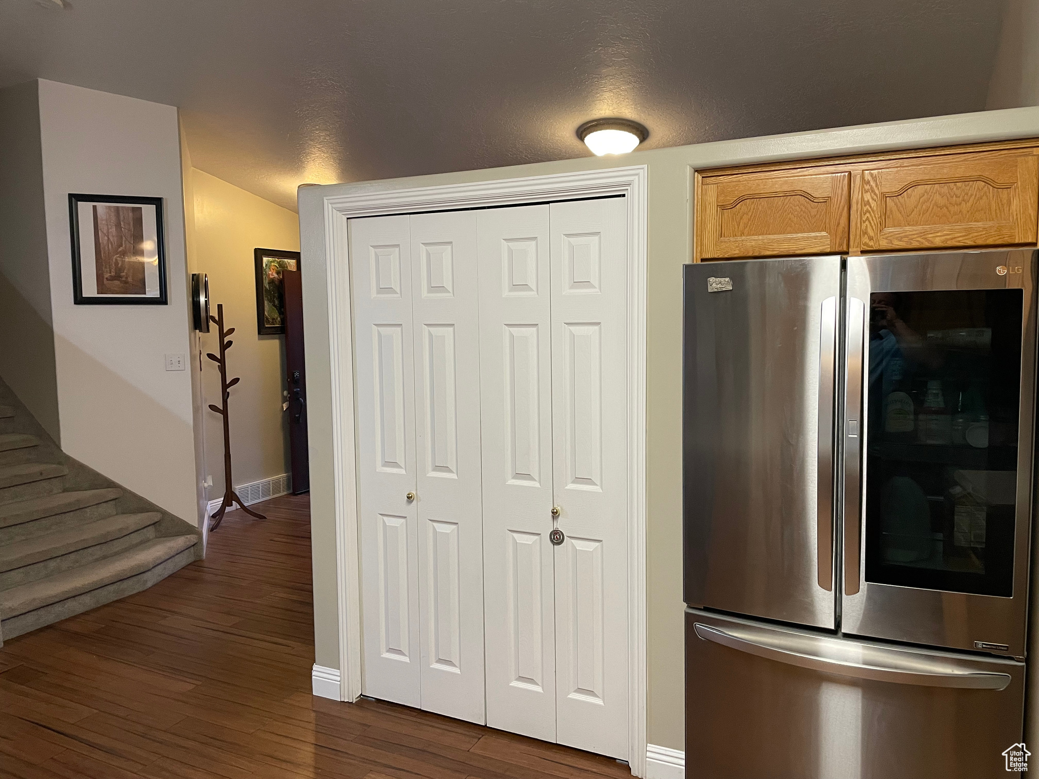 Kitchen with stainless steel fridge, lofted ceiling, and dark wood-type flooring