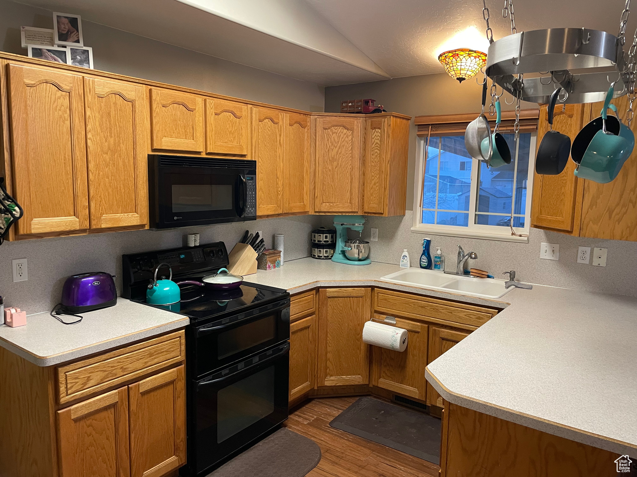 Kitchen featuring sink, black appliances, and wood-type flooring