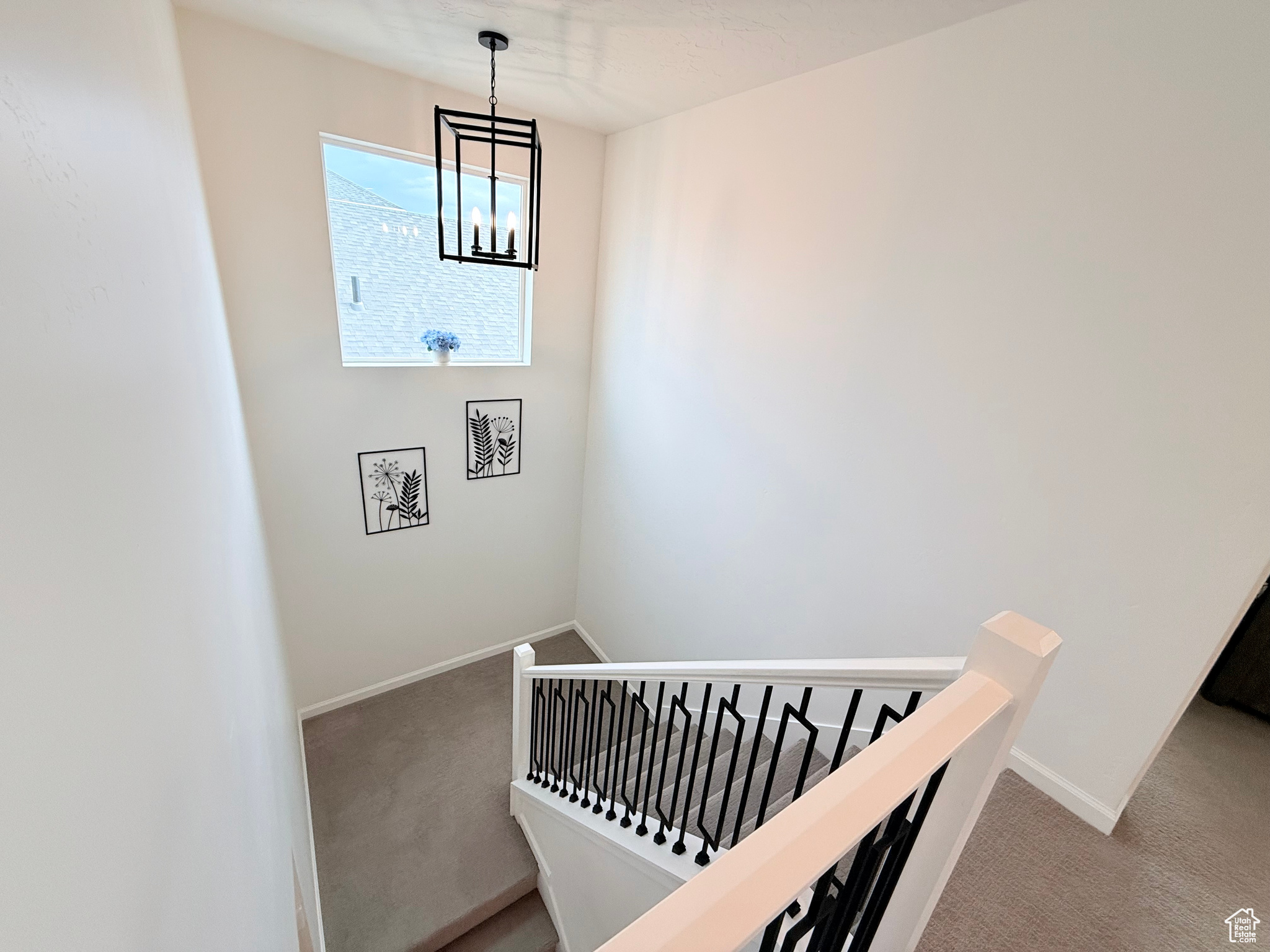 Staircase with carpet floors and a notable chandelier at top level