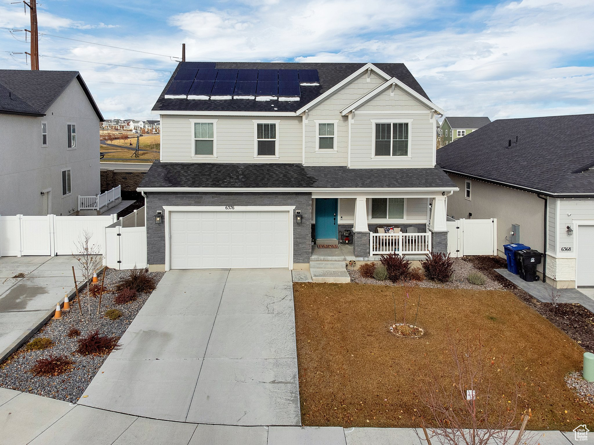 Front facade with a front lawn, covered porch, a garage, and solar panels