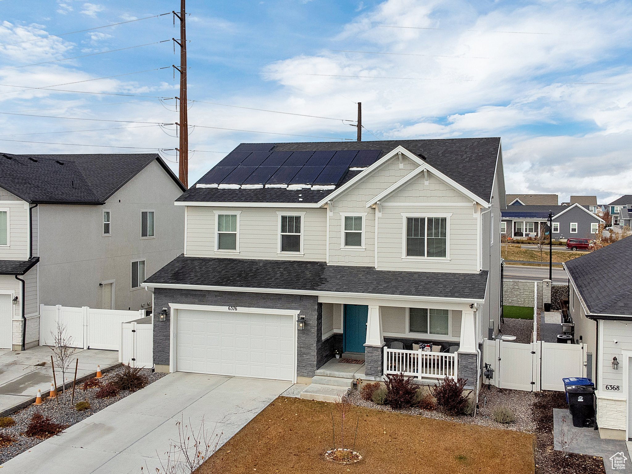 View of front of home with solar panels, a porch, and a garage