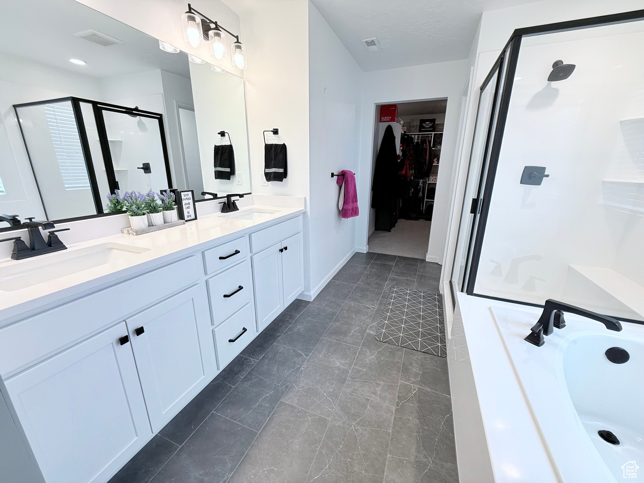 Primary Bathroom on 2nd Floor featuring double vanity, separate tub/shower and walk in closet with white cabinets