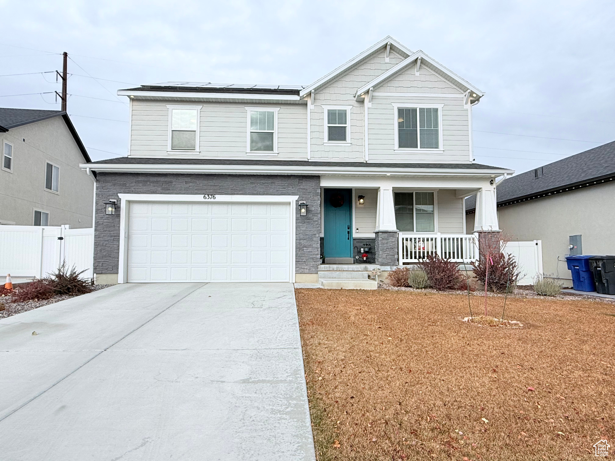 View of front of property featuring solar panels, a porch, and a garage