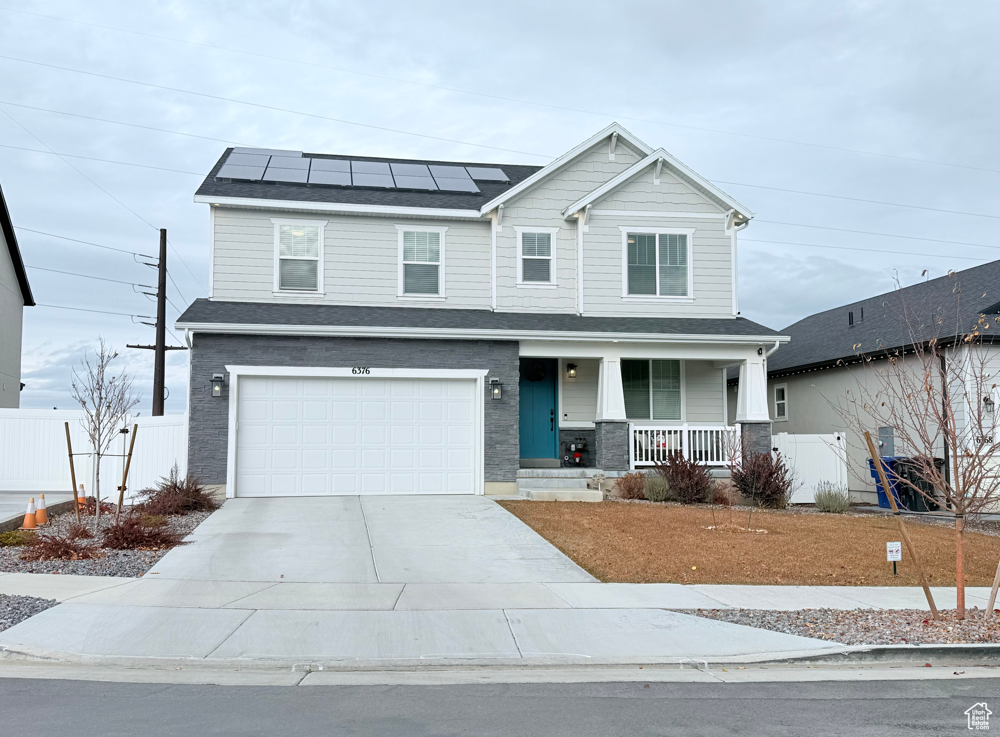 View of front of property featuring covered porch, solar panels, and a garage