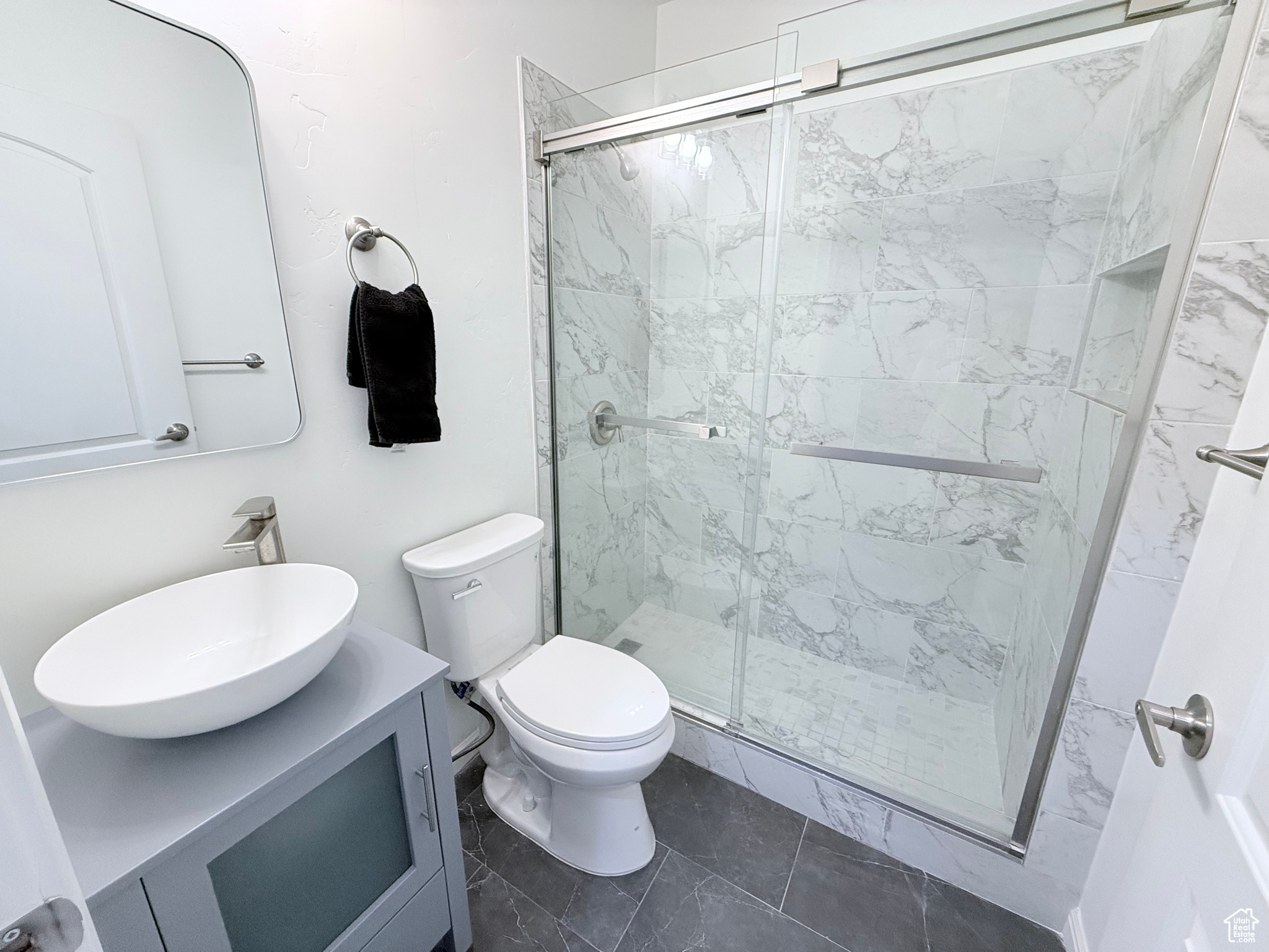 Bathroom featuring toilet, an enclosed shower, and vanity in basement