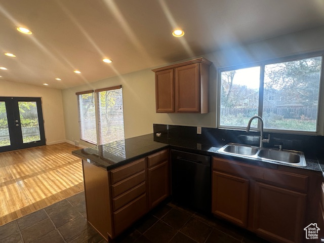 Kitchen featuring kitchen peninsula, sink, dishwasher, dark hardwood / wood-style floors, and lofted ceiling