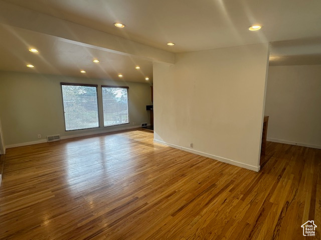 Spare room with beam ceiling and wood-type flooring