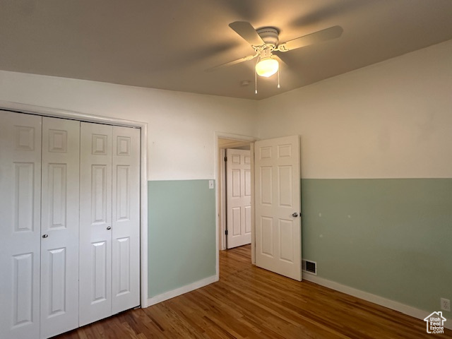 Unfurnished bedroom featuring a closet, ceiling fan, and dark hardwood / wood-style flooring