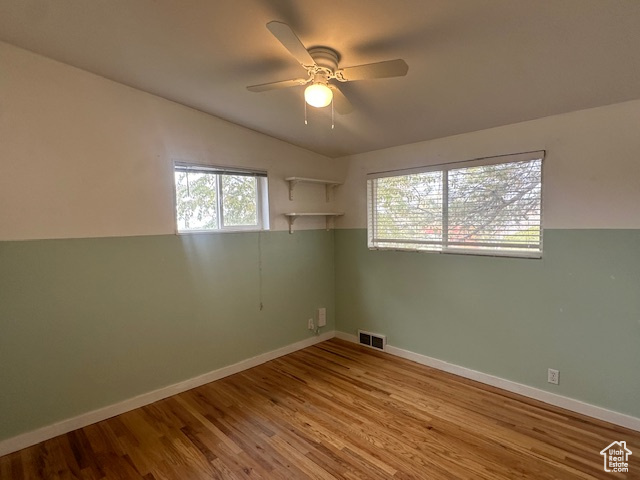 Spare room with plenty of natural light, ceiling fan, light wood-type flooring, and vaulted ceiling