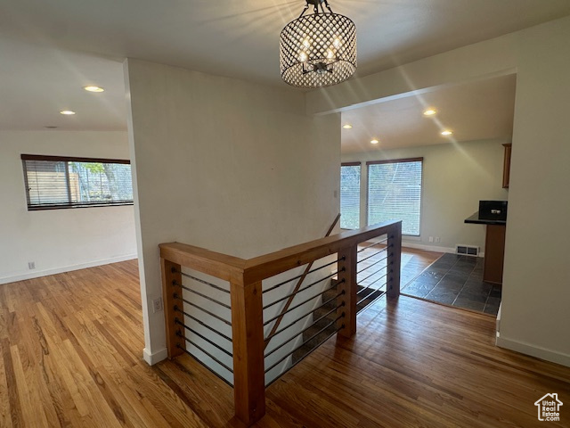 Hall featuring vaulted ceiling, plenty of natural light, dark wood-type flooring, and a notable chandelier