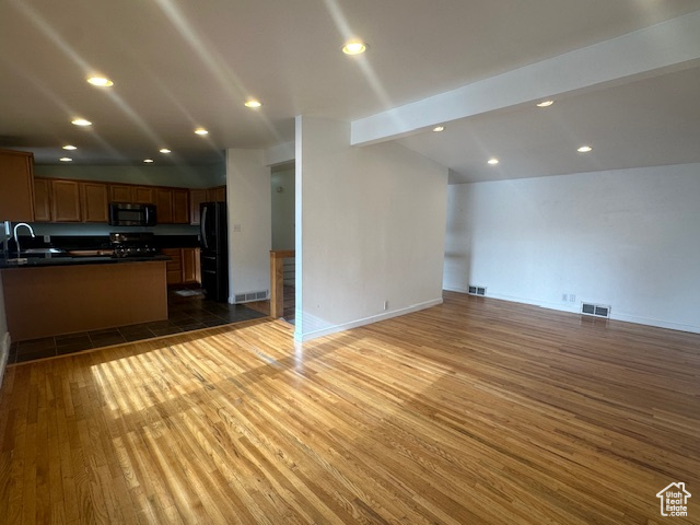 Kitchen featuring black refrigerator, lofted ceiling with beams, dark hardwood / wood-style floors, and sink