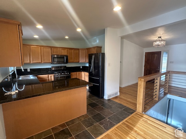 Kitchen with hanging light fixtures, stainless steel appliances, dark hardwood / wood-style floors, kitchen peninsula, and vaulted ceiling