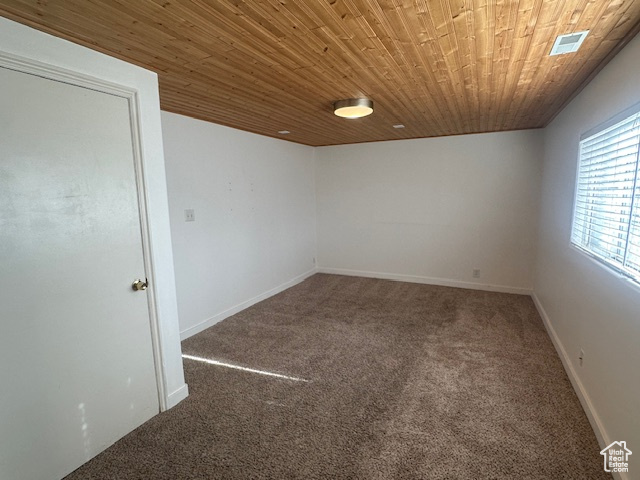 Carpeted spare room featuring wood ceiling