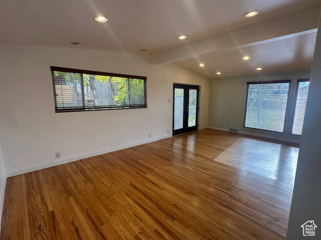 Spare room with hardwood / wood-style floors, vaulted ceiling with beams, and french doors