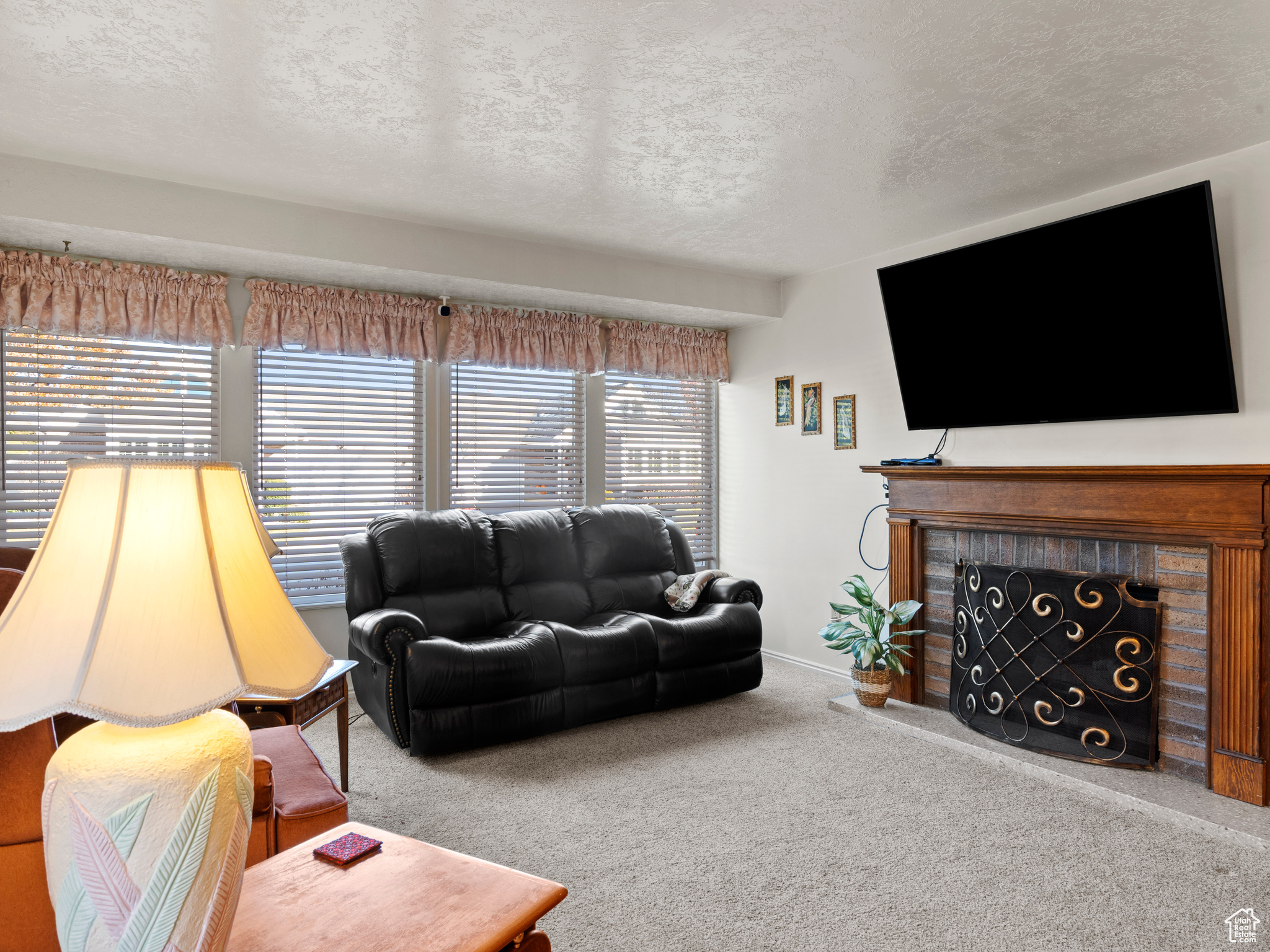 Carpeted living room with a fireplace and a textured ceiling