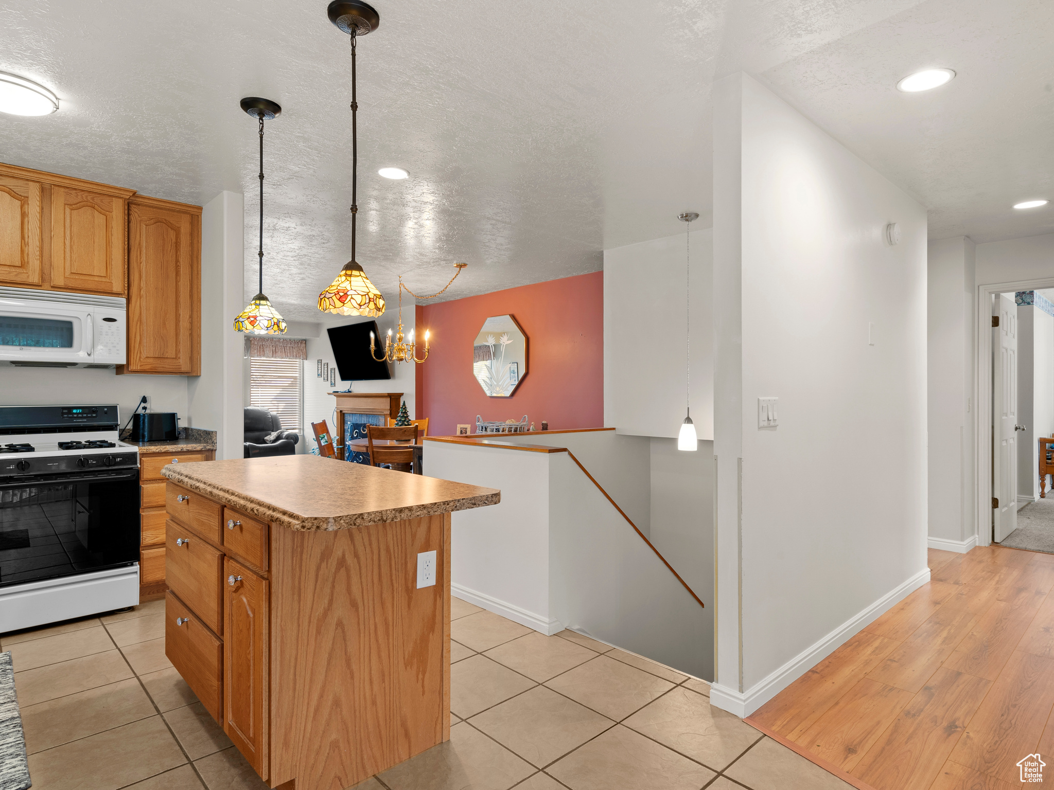 Kitchen featuring pendant lighting, white appliances, a center island, and an inviting chandelier