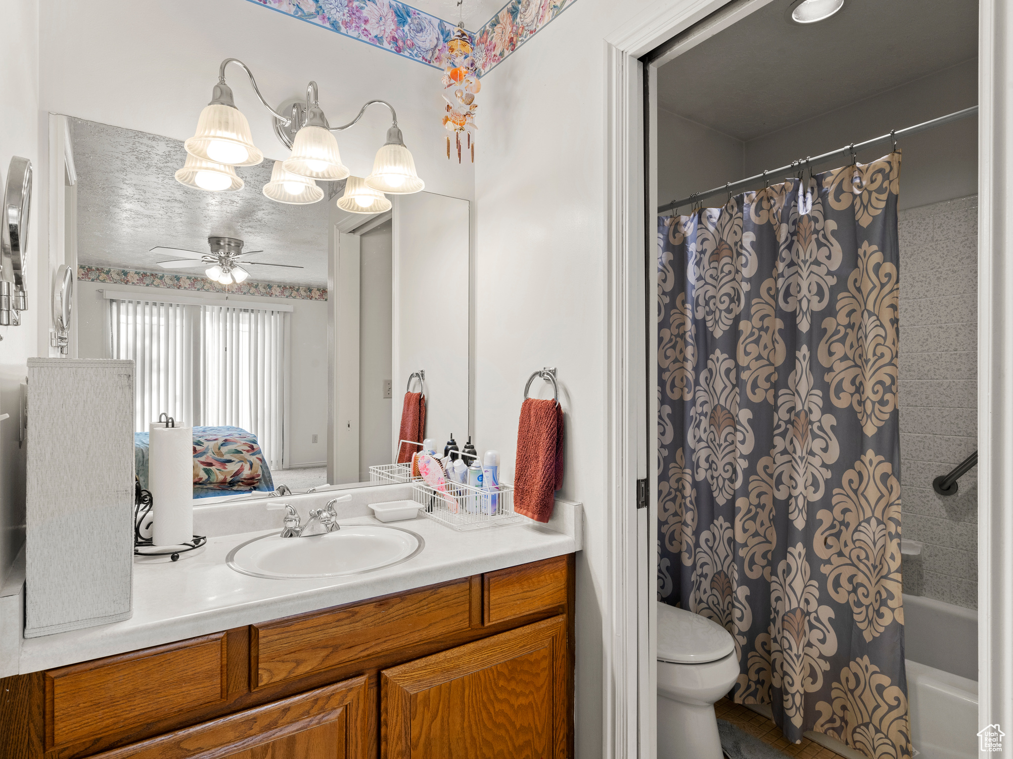 Full bathroom featuring ceiling fan, toilet, shower / bathtub combination with curtain, and vanity