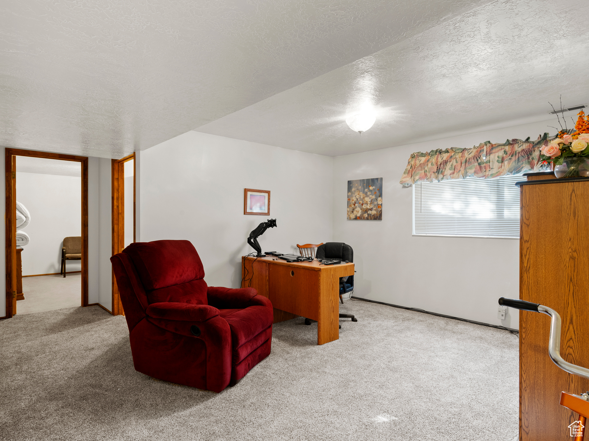 Carpeted home office with a textured ceiling