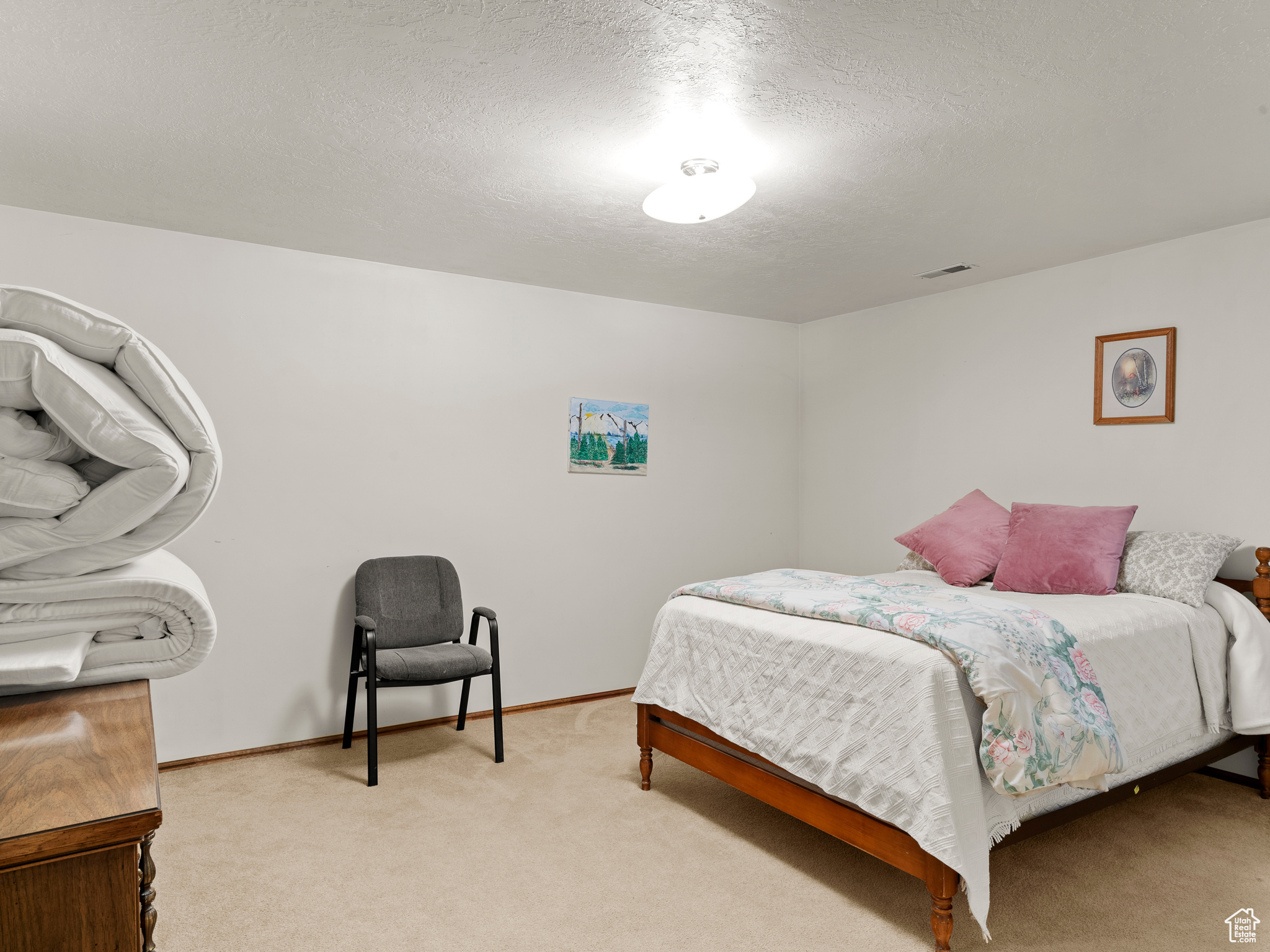 Bedroom with a textured ceiling and light colored carpet