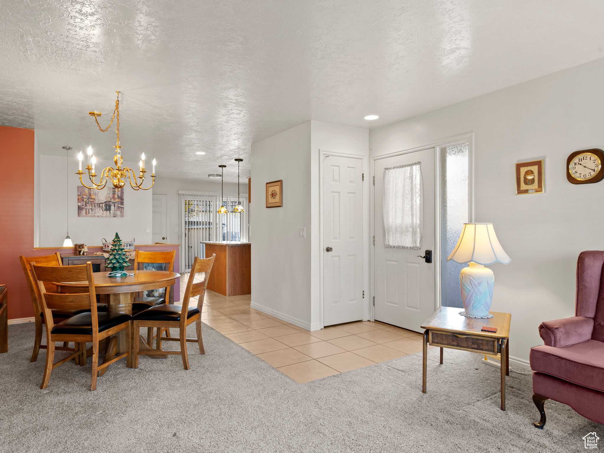 Dining area featuring light carpet, a textured ceiling, and an inviting chandelier