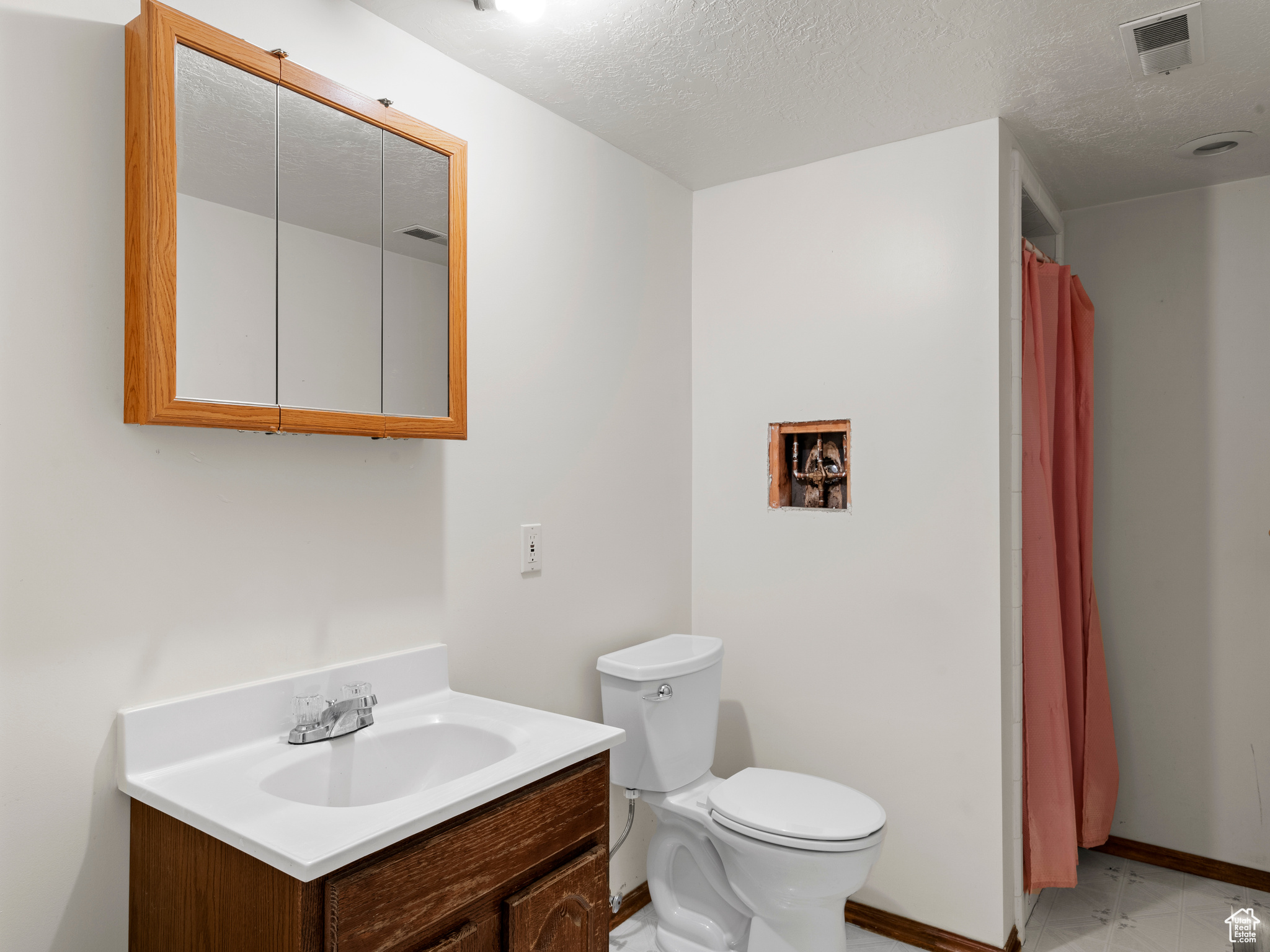 Bathroom featuring vanity, a textured ceiling, and toilet