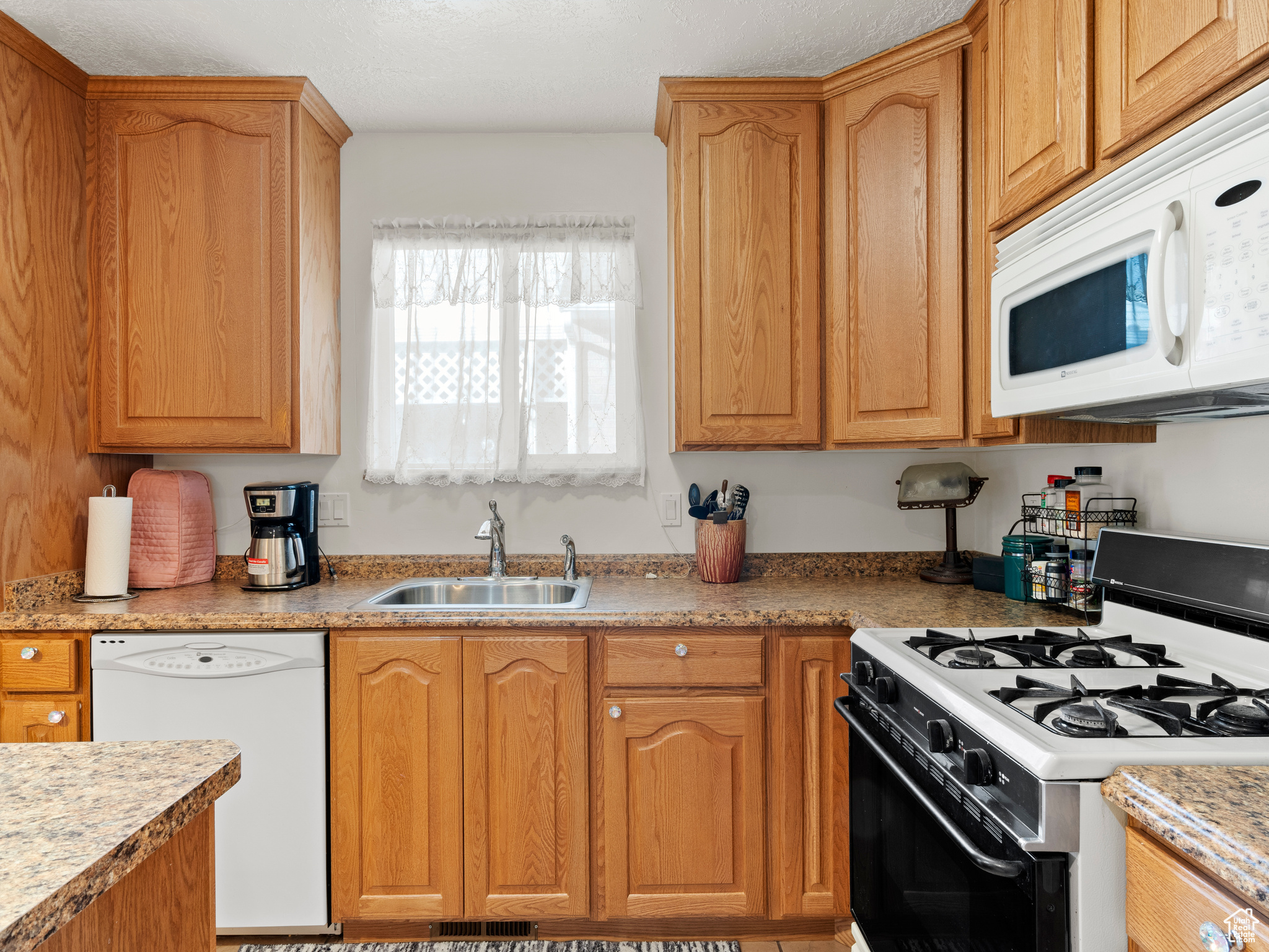 Kitchen featuring white appliances and sink