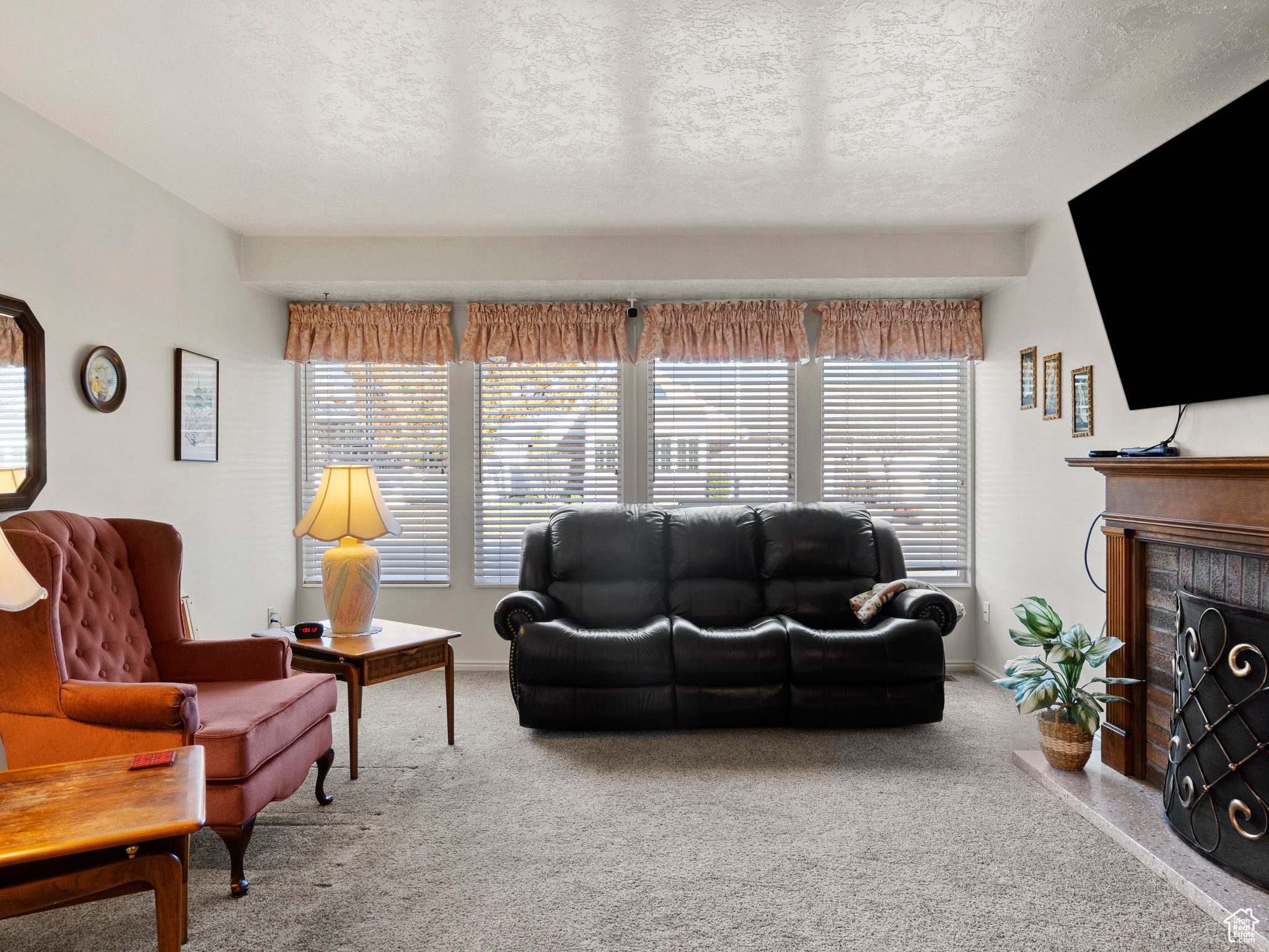 Carpeted living room featuring a textured ceiling and a brick fireplace