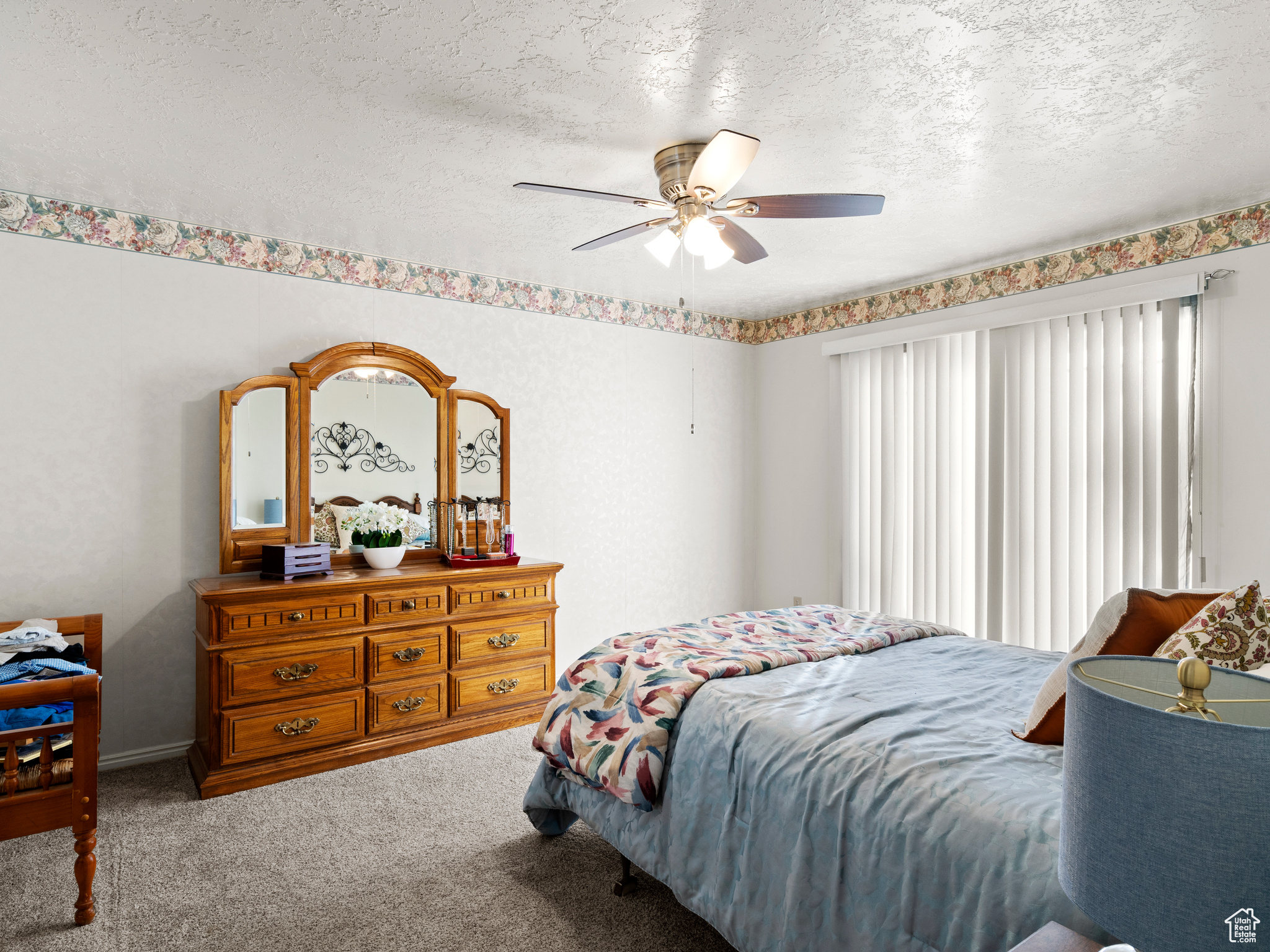 Carpeted bedroom with ceiling fan and a textured ceiling