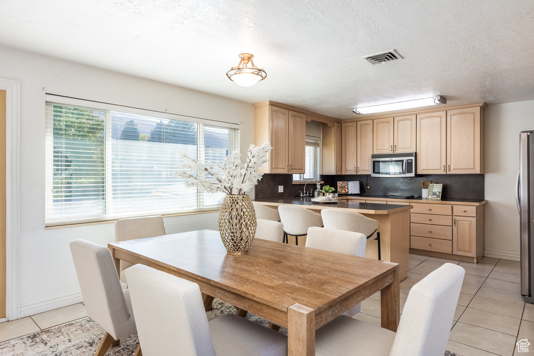 Dining space with light tile patterned floors, a textured ceiling, and sink