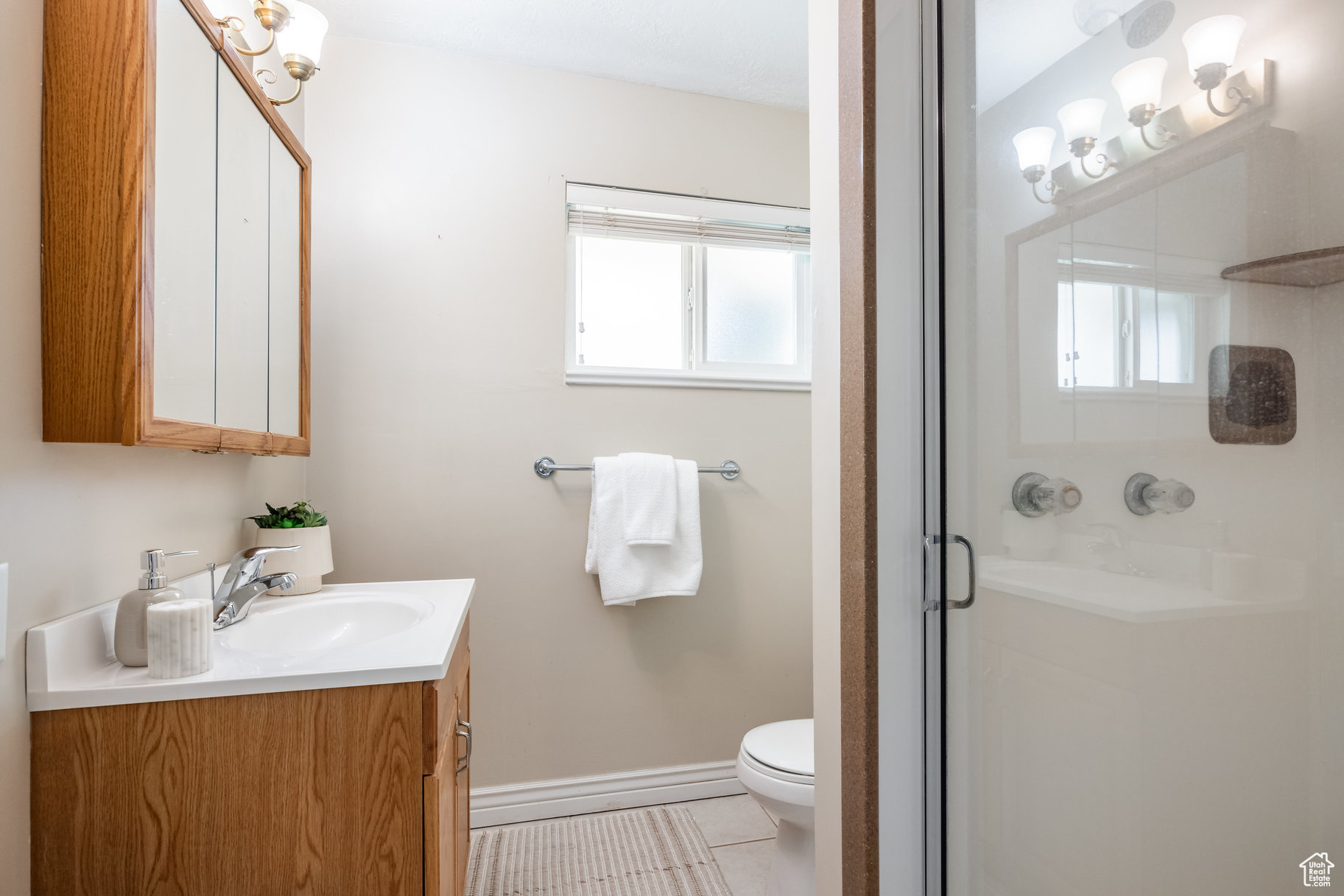 Bathroom with tile patterned floors, plenty of natural light, walk in shower, and vanity