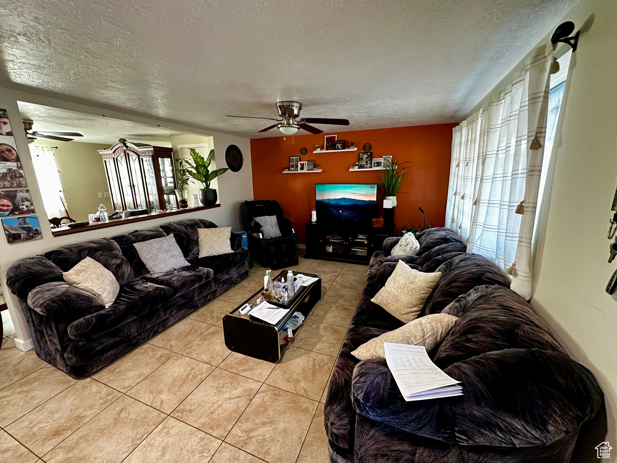 Living room with ceiling fan, light tile patterned flooring, and a textured ceiling