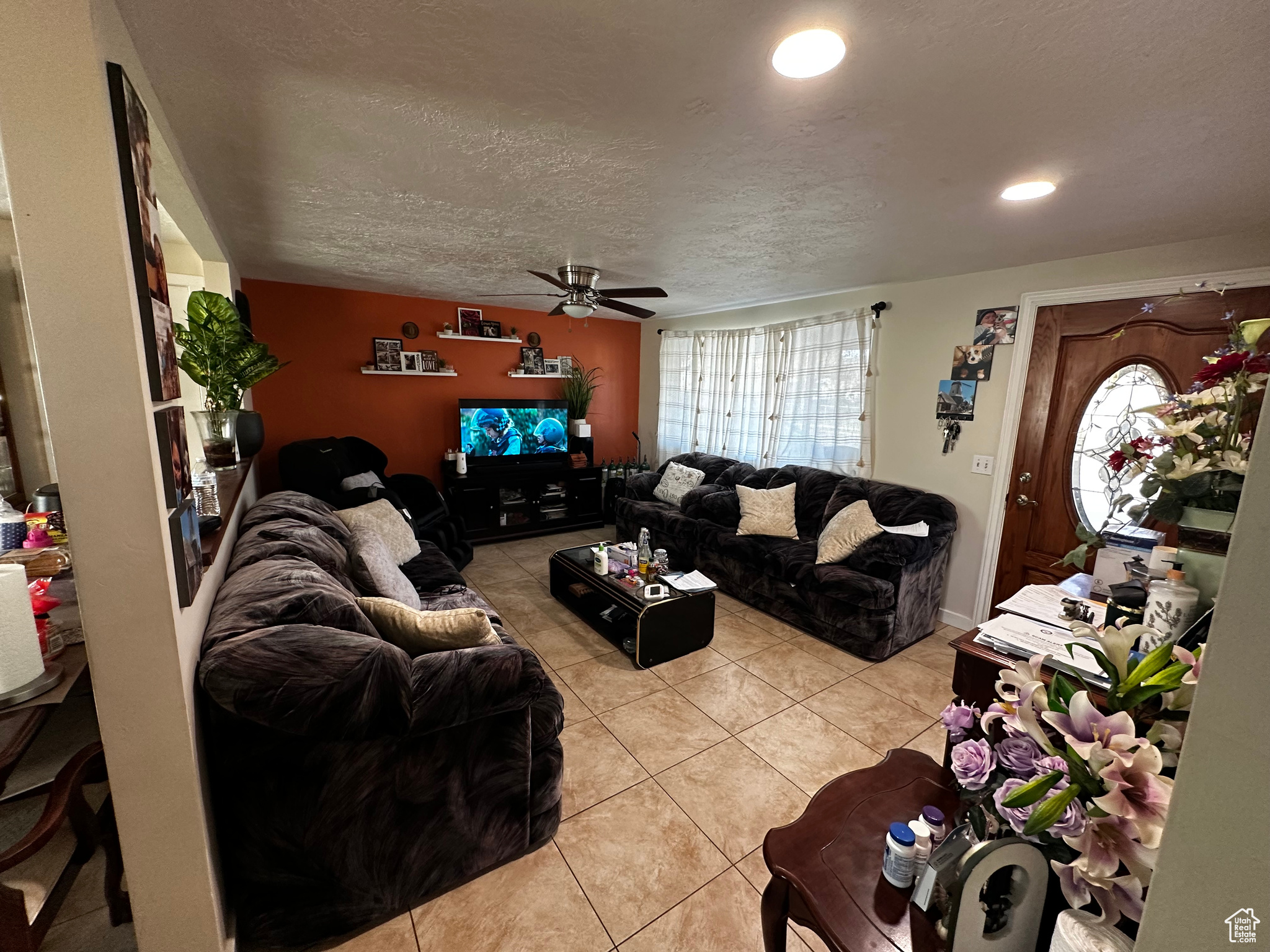 Living room featuring ceiling fan, light tile patterned floors, and a textured ceiling