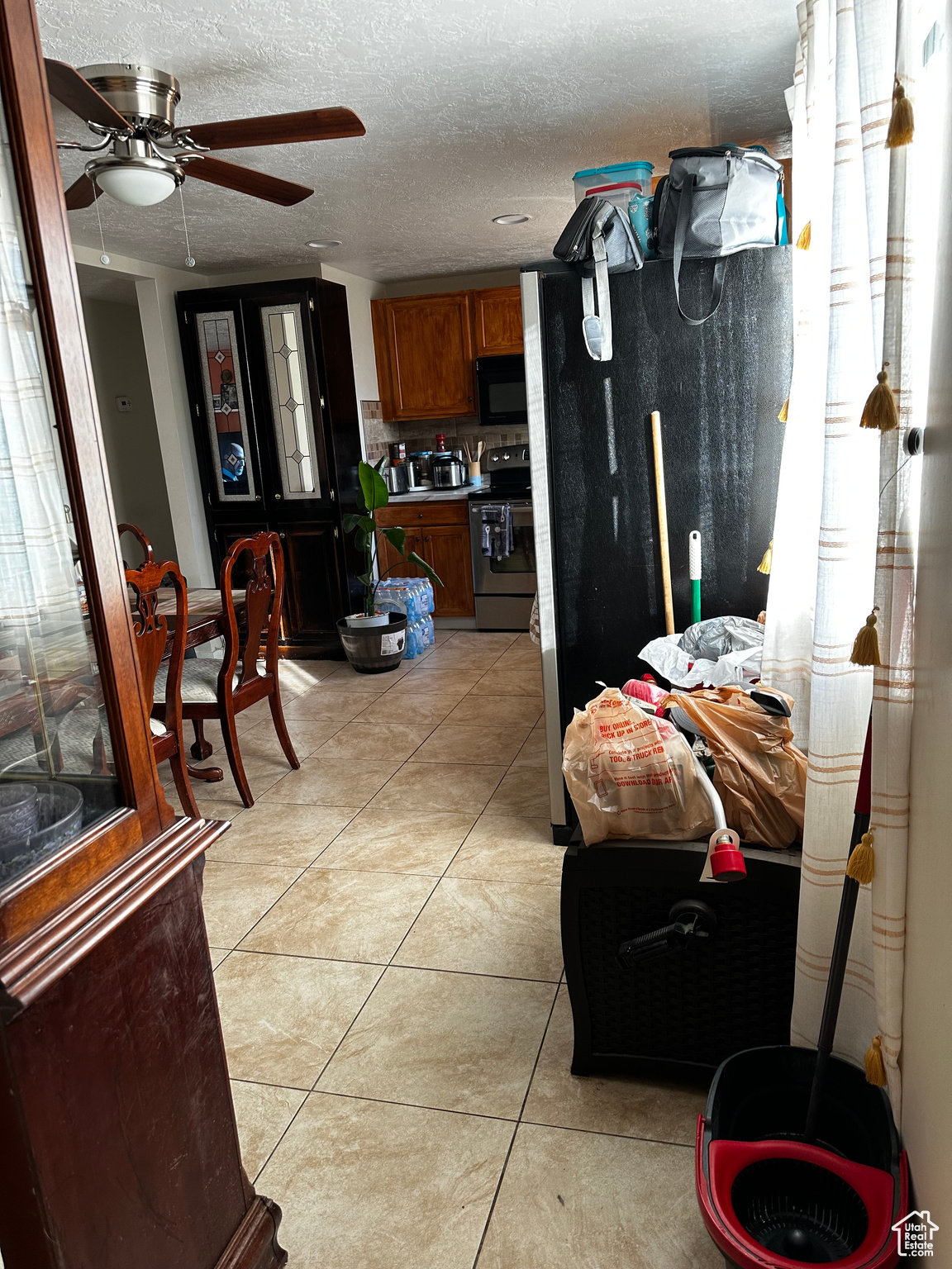 Kitchen with backsplash, a textured ceiling, ceiling fan, light tile patterned floors, and electric range