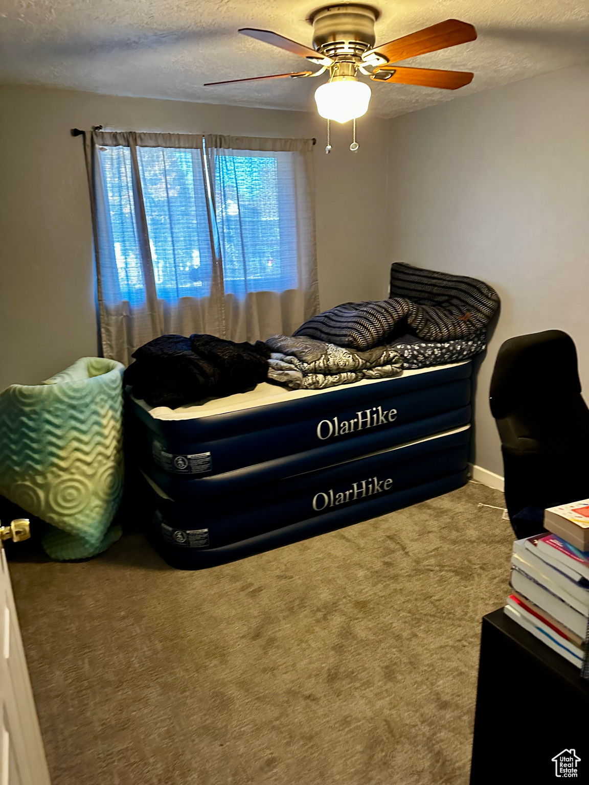 Carpeted bedroom with ceiling fan and a textured ceiling