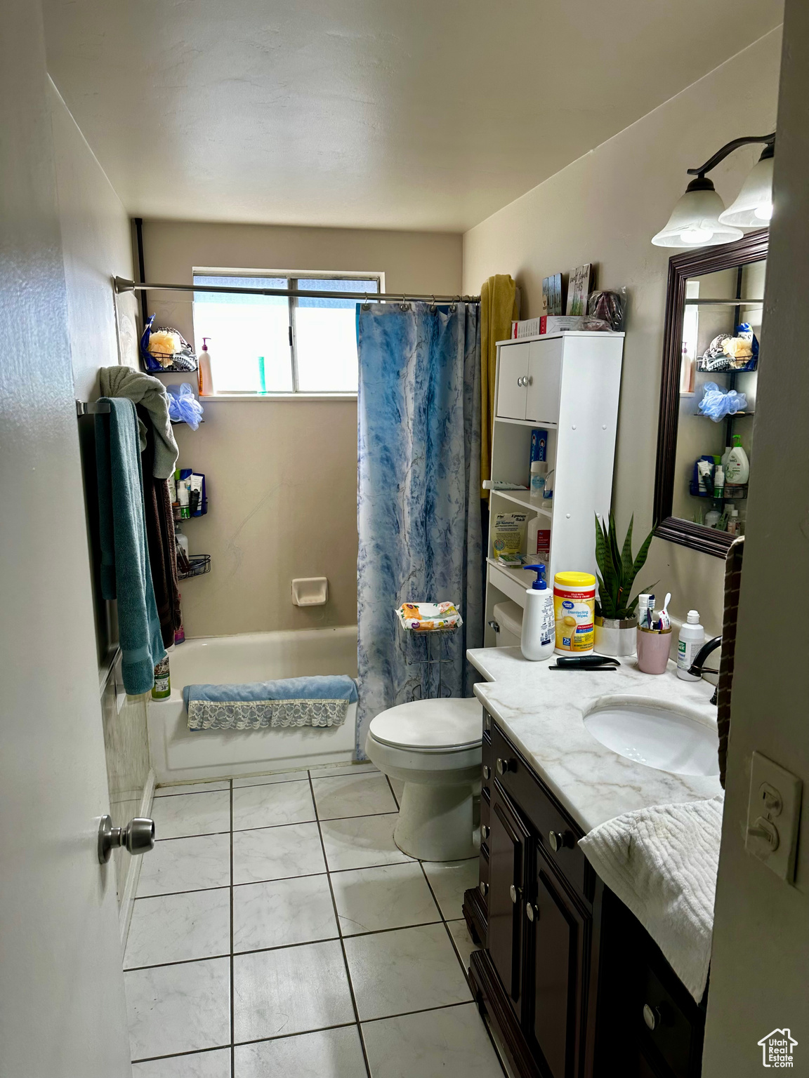 Full bathroom with toilet, tile patterned flooring, vanity, and shower / tub combo with curtain