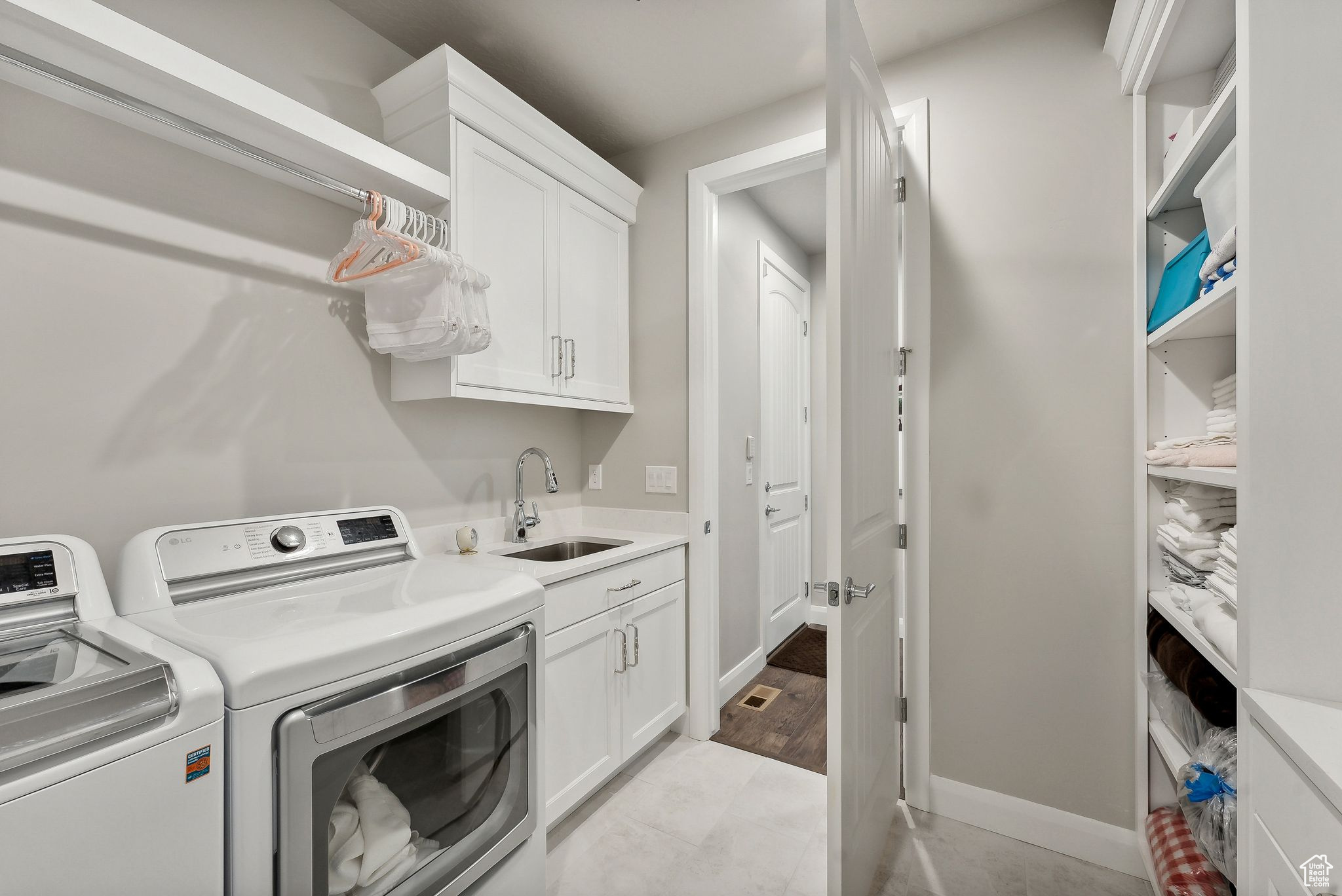 Clothes washing area with cabinets, independent washer and dryer, light hardwood / wood-style floors, and sink