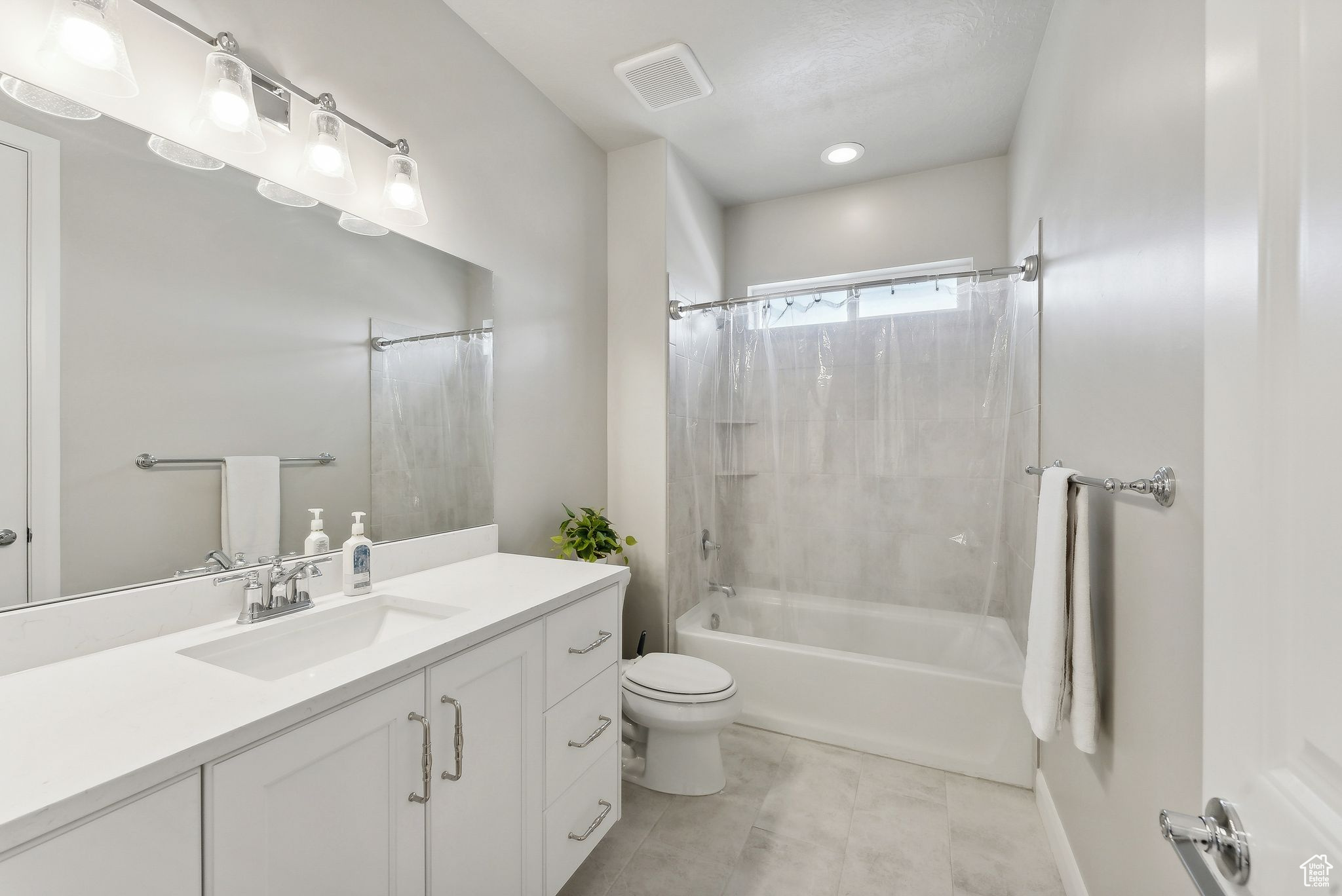 Full bathroom with vanity, tile patterned floors, toilet, shower / bathtub combination with curtain, and a textured ceiling